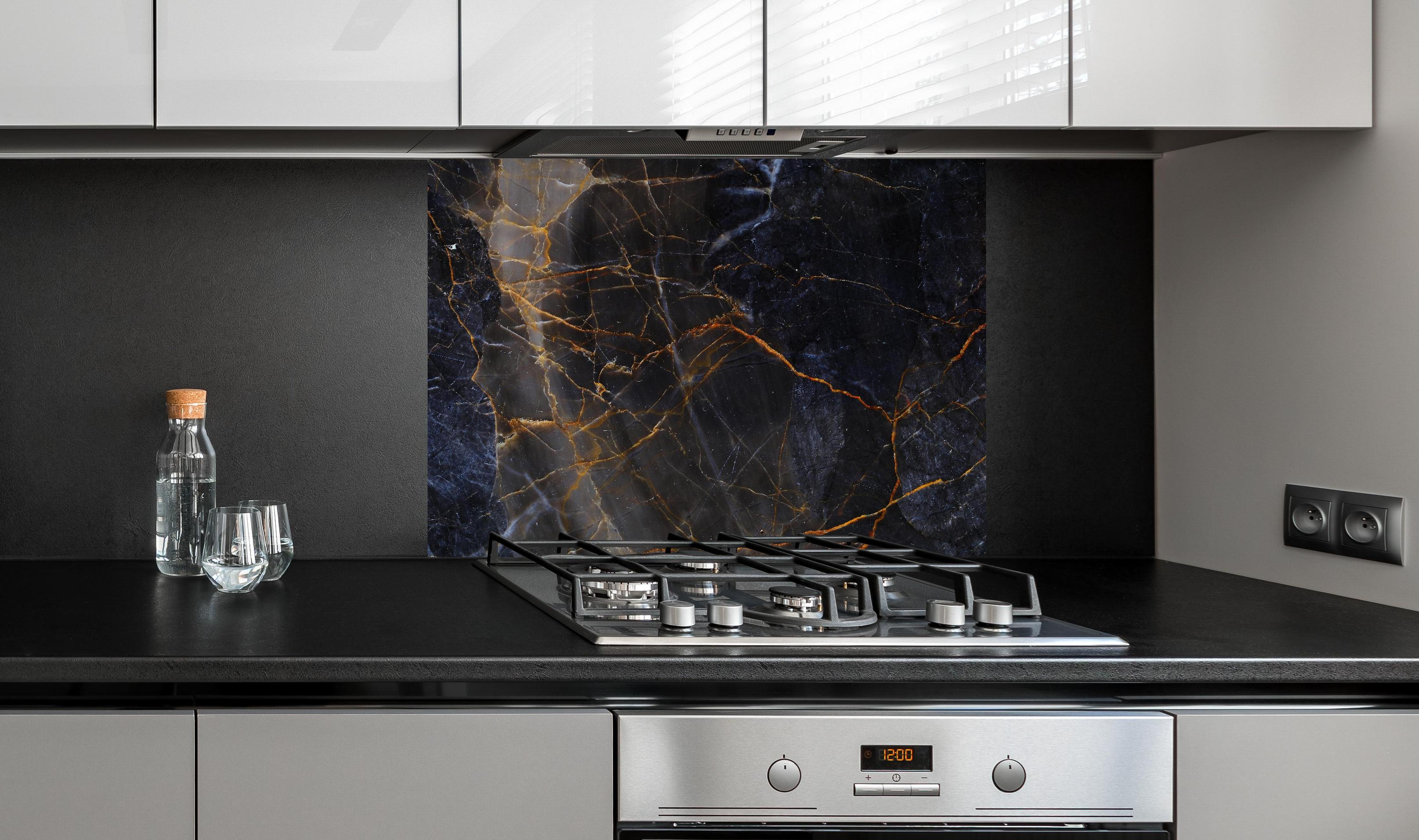 Spritzschutz - Schwarz und braune Marmor Textur aus Russland hinter einem Cerankochfeld zwischen Holz-Kochutensilien