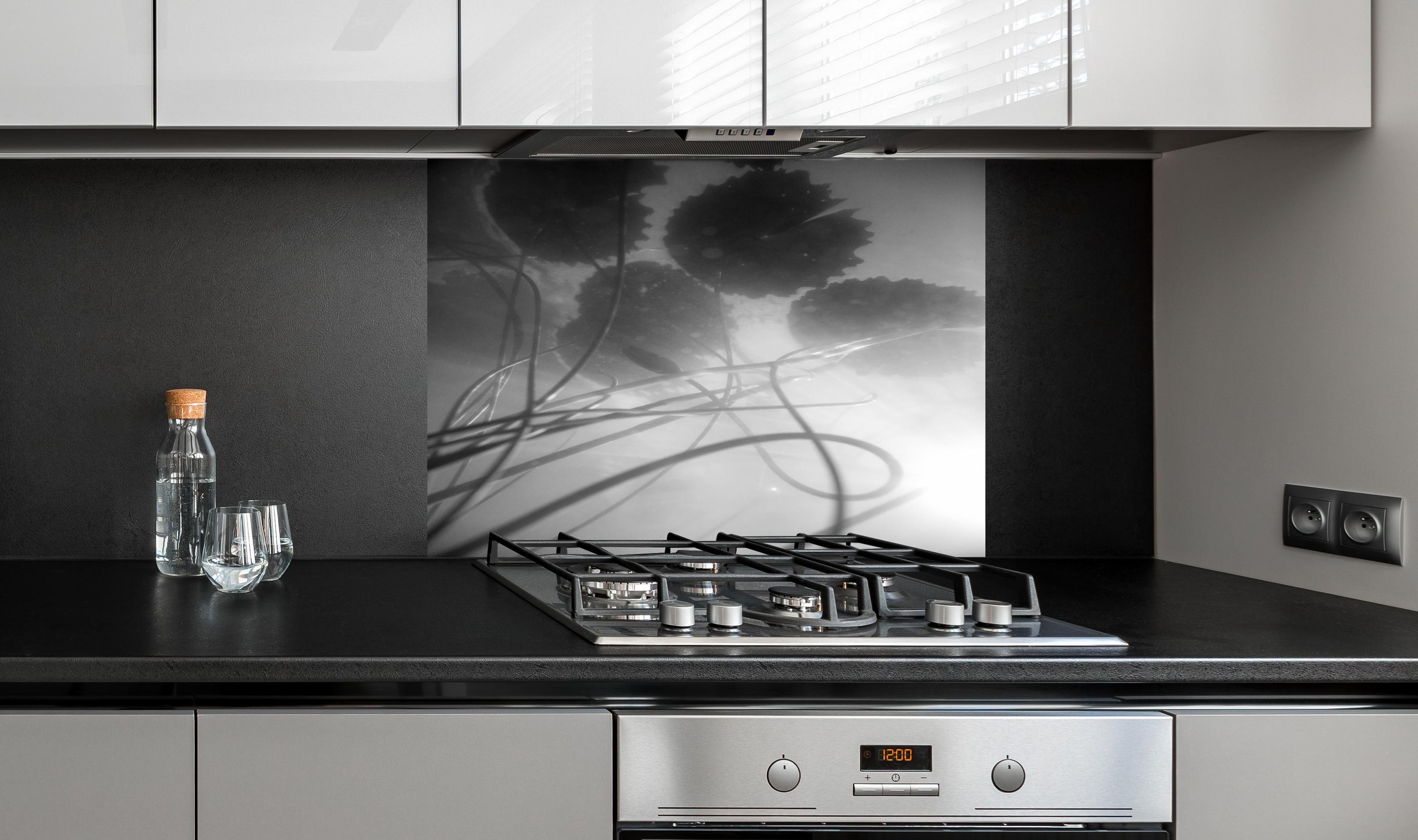 Spritzschutz - Schwarz-weiße Nahaufnahme der Water Lily hinter einem Cerankochfeld zwischen Holz-Kochutensilien