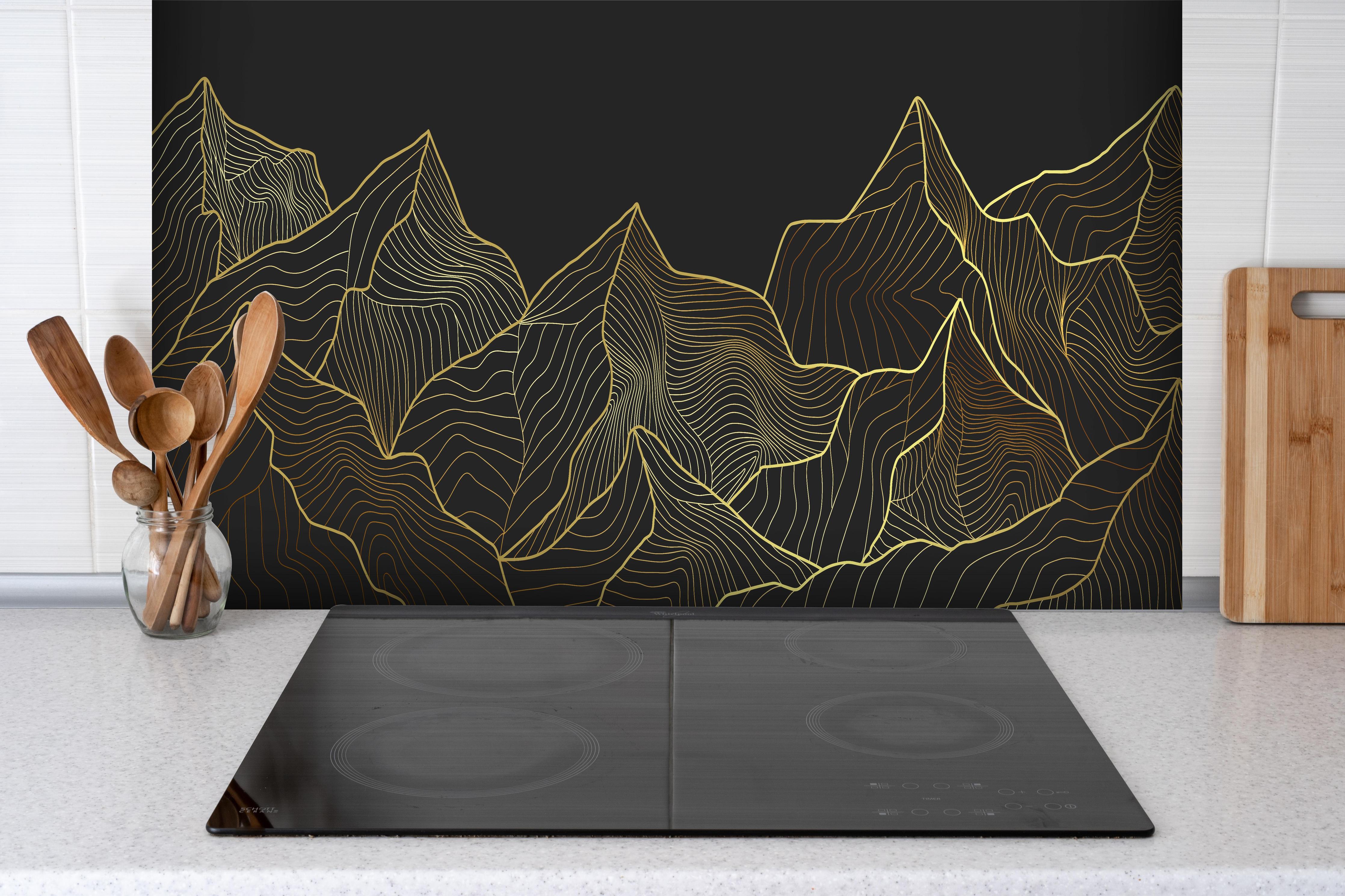 Spritzschutz - Schwarze Berge mit goldener Linienkunst hinter einem Cerankochfeld zwischen Holz-Kochutensilien