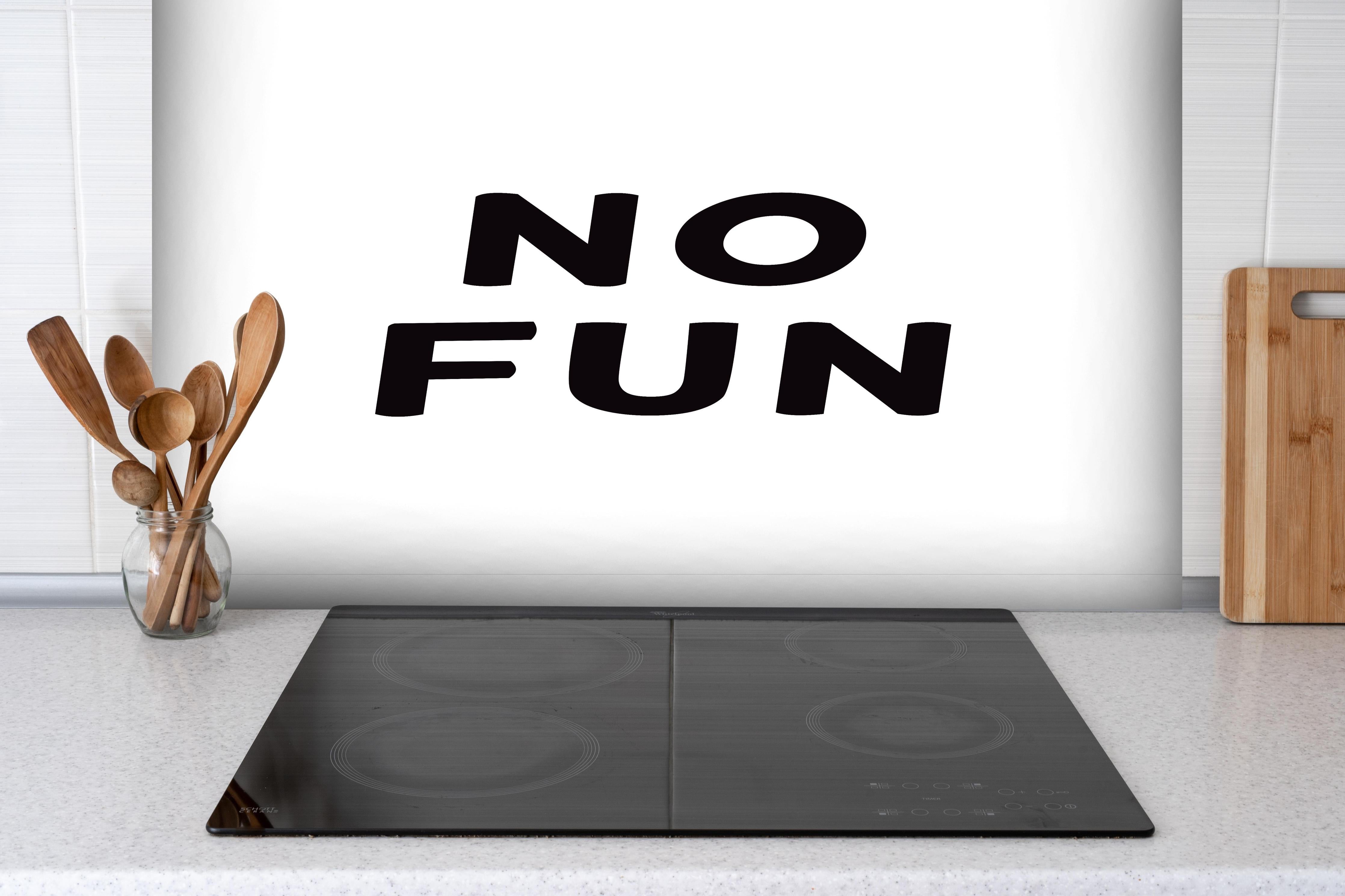 Spritzschutz - Schwarze Typografie 'No Fun' auf Weiß hinter einem Cerankochfeld zwischen Holz-Kochutensilien