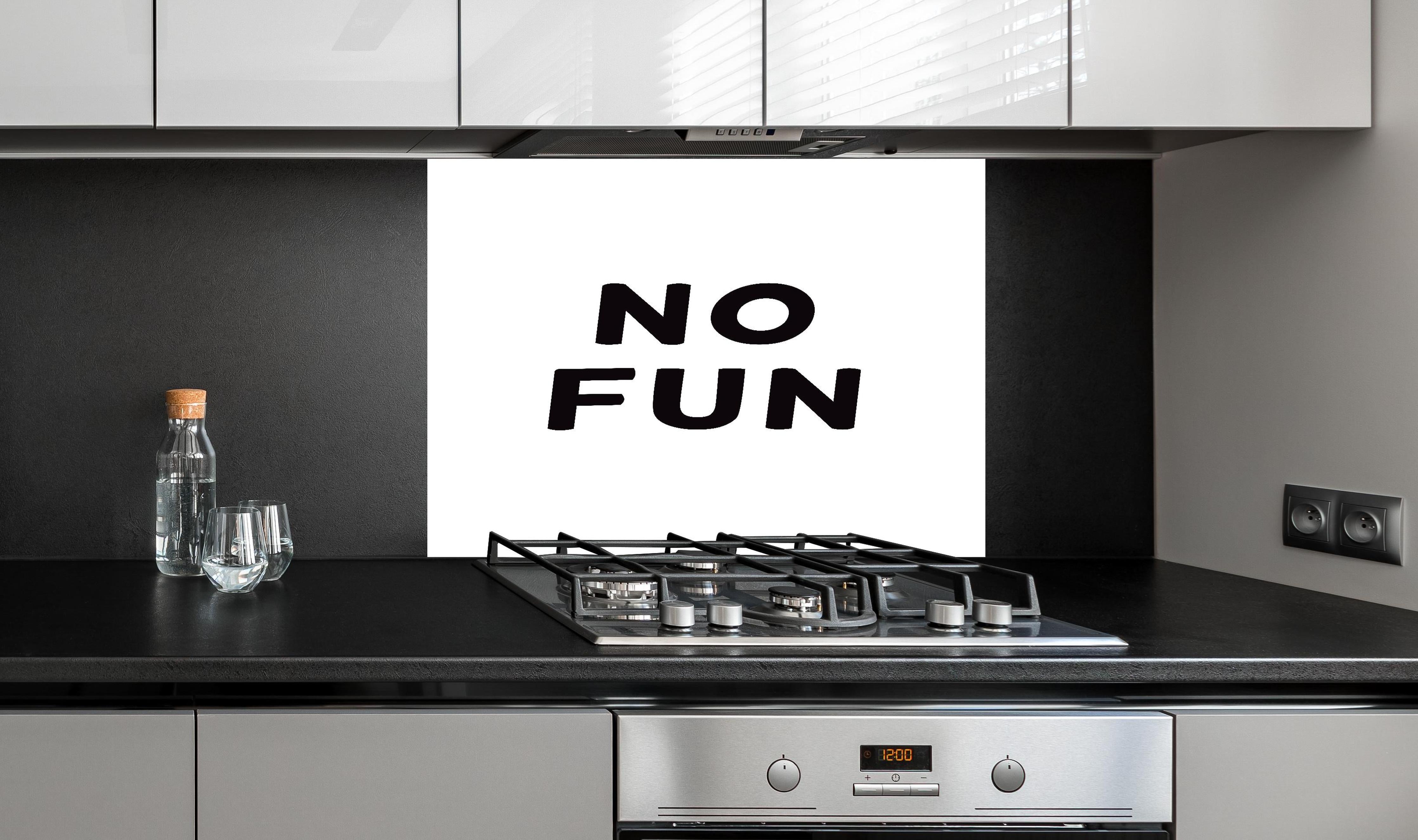 Spritzschutz - Schwarze Typografie 'No Fun' auf Weiß hinter einem Cerankochfeld zwischen Holz-Kochutensilien