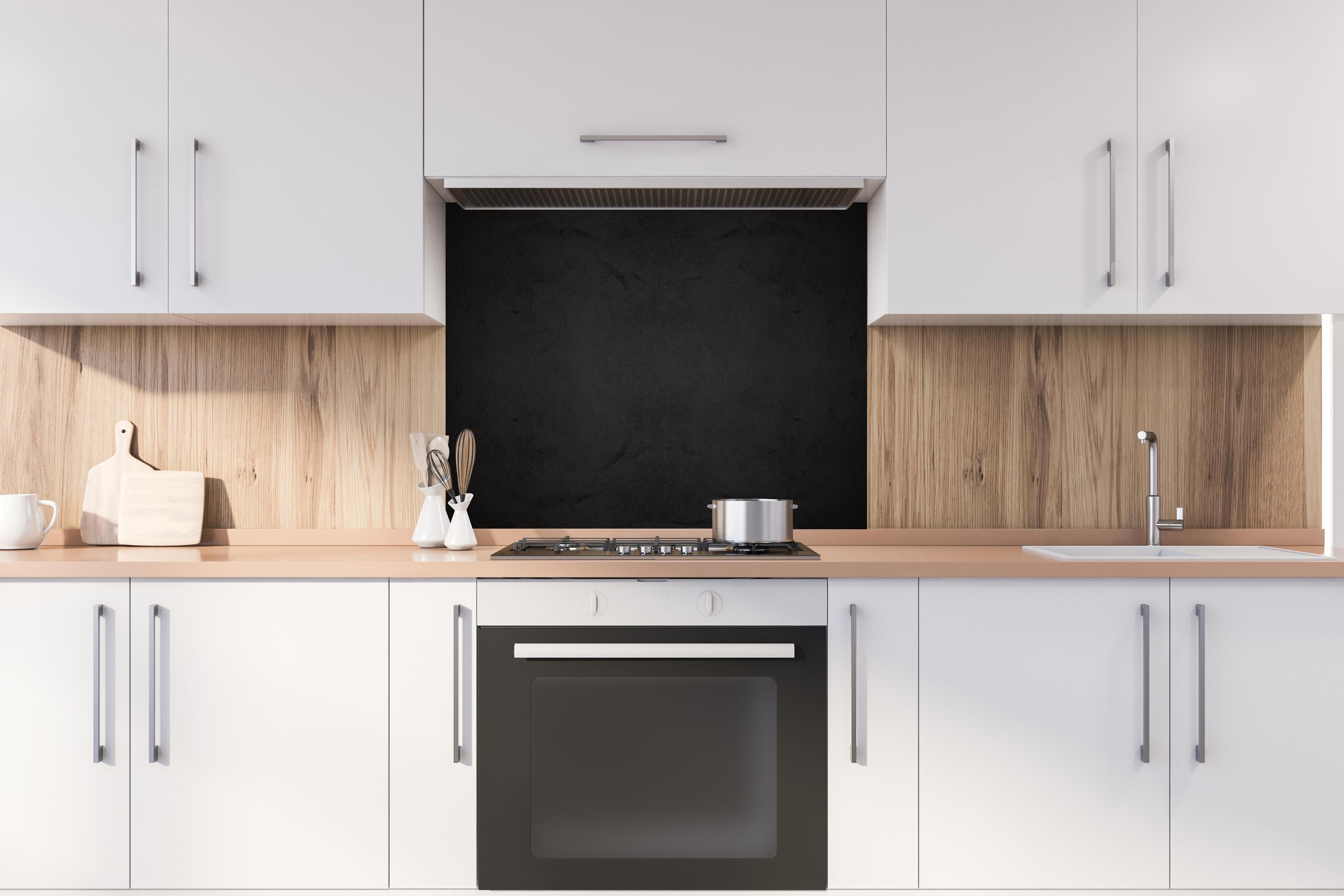 Spritzschutz - Schwarze anthrazit Textur hinter einem Cerankochfeld zwischen Holz-Kochutensilien