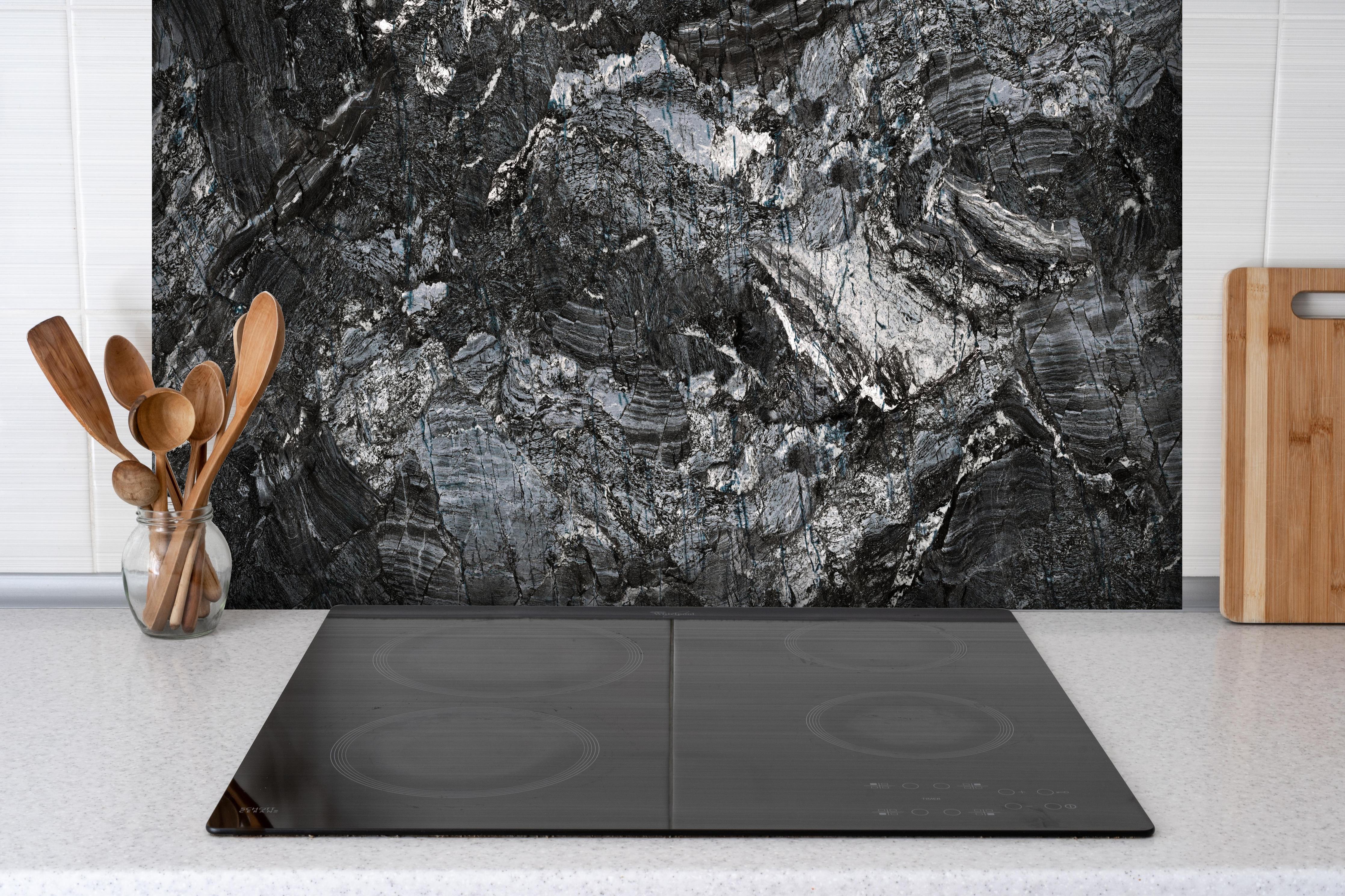 Spritzschutz - Schwarzer Marmor - Natur hinter einem Cerankochfeld zwischen Holz-Kochutensilien