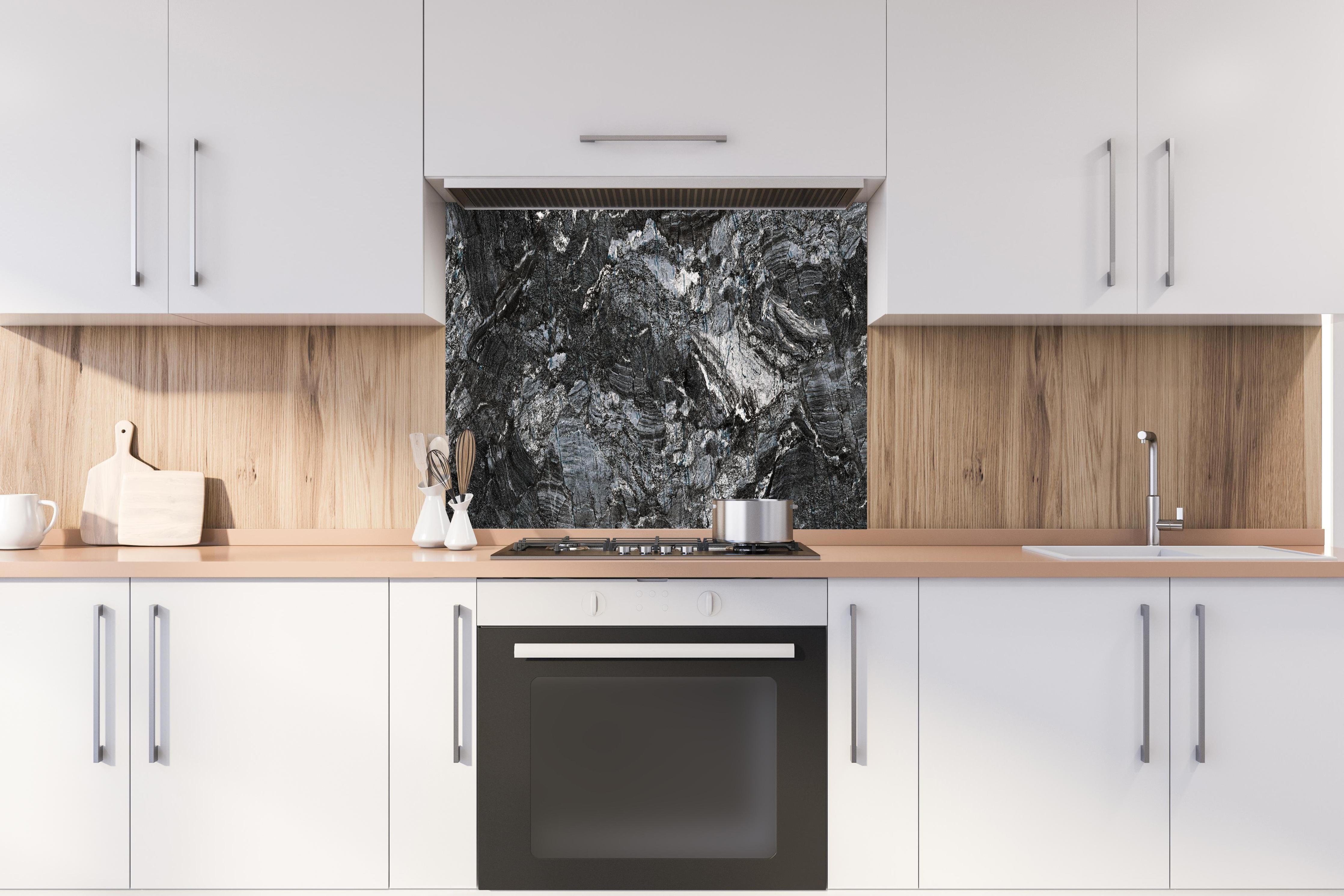 Spritzschutz - Schwarzer Marmor - Natur hinter einem Cerankochfeld zwischen Holz-Kochutensilien