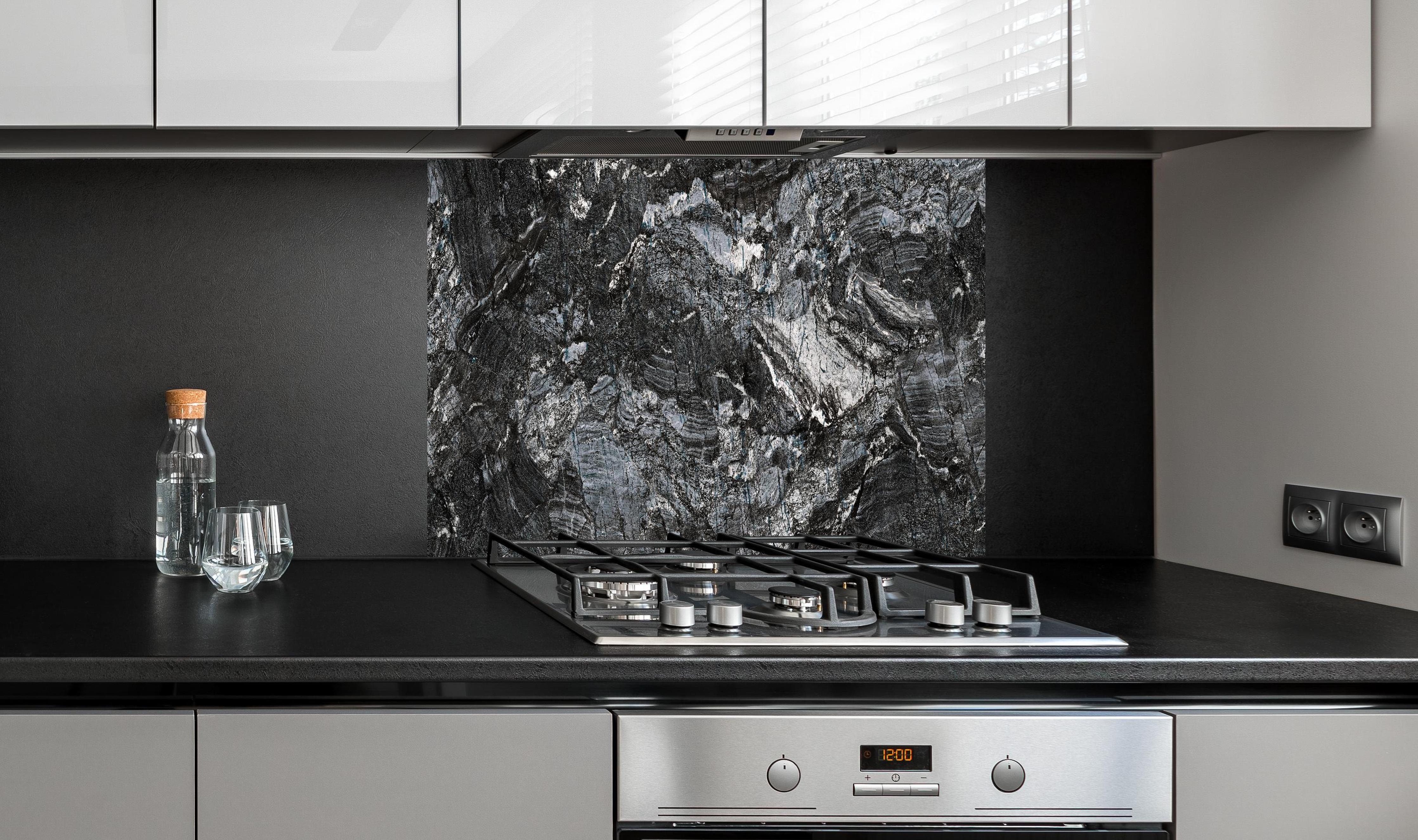 Spritzschutz - Schwarzer Marmor - Natur hinter einem Cerankochfeld zwischen Holz-Kochutensilien