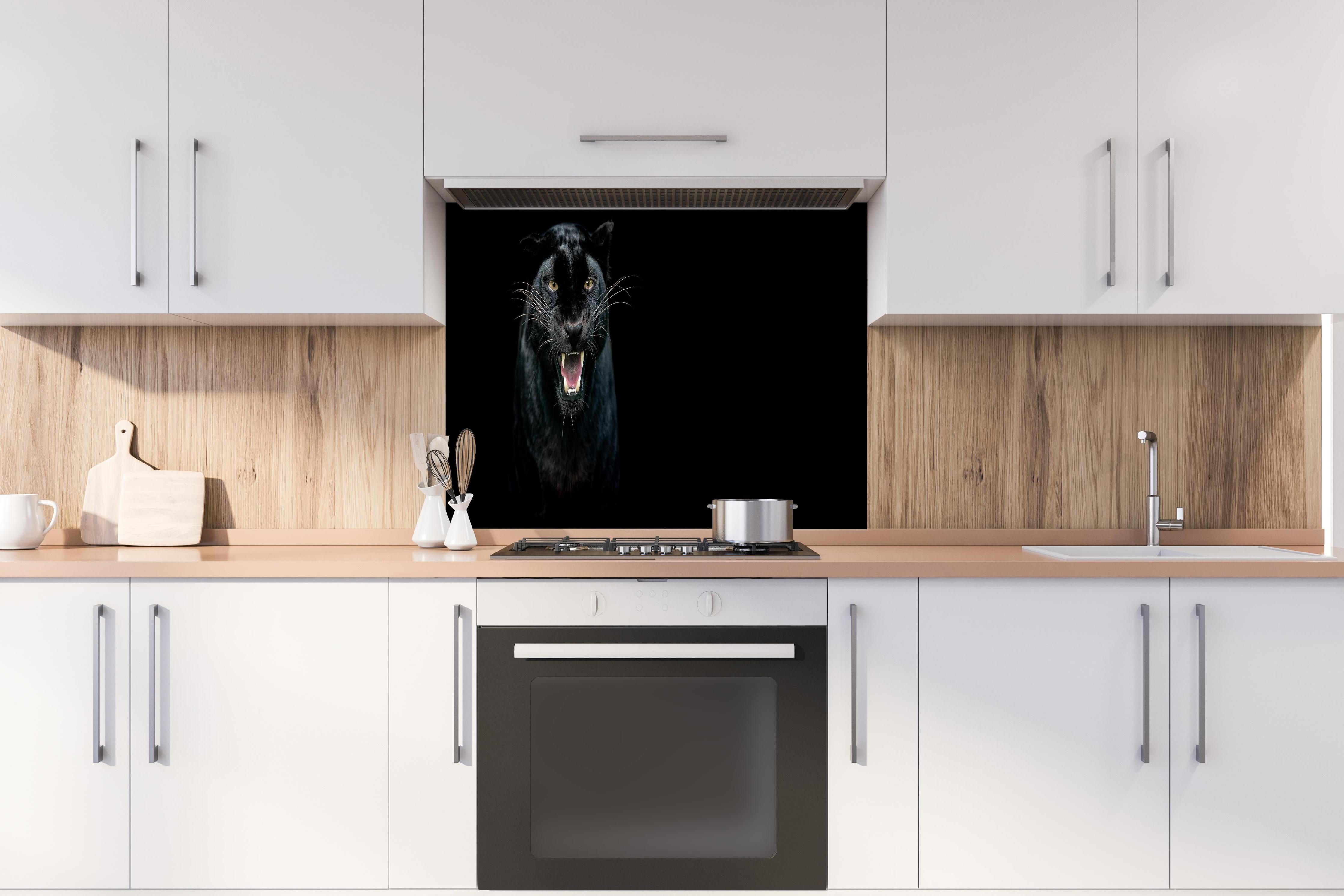 Spritzschutz - Schwarzer Panther auf schwarzem Hintergrund hinter einem Cerankochfeld zwischen Holz-Kochutensilien