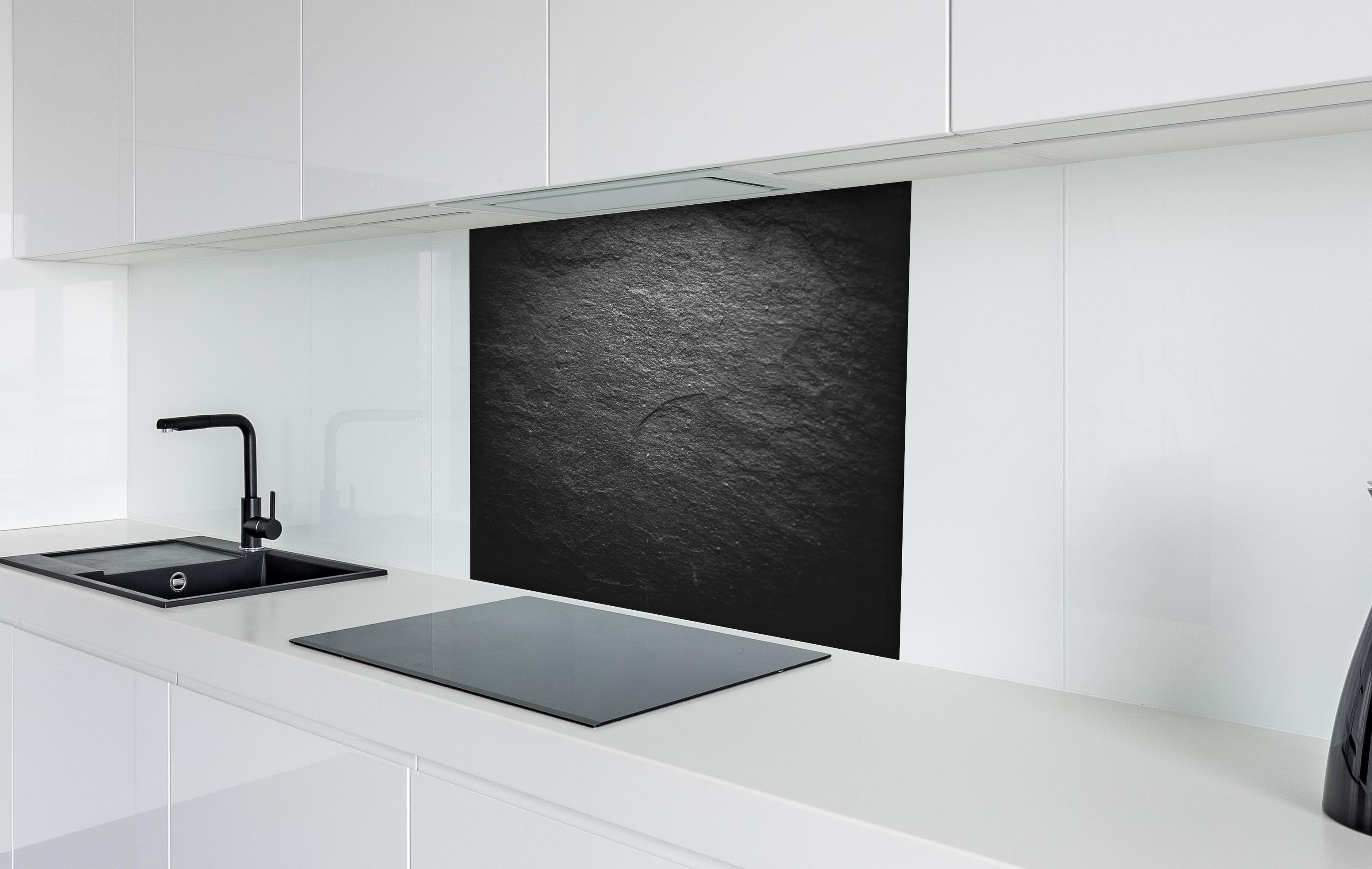 Spritzschutz - Schwarzer Schieferstein hinter einem Cerankochfeld zwischen Holz-Kochutensilien