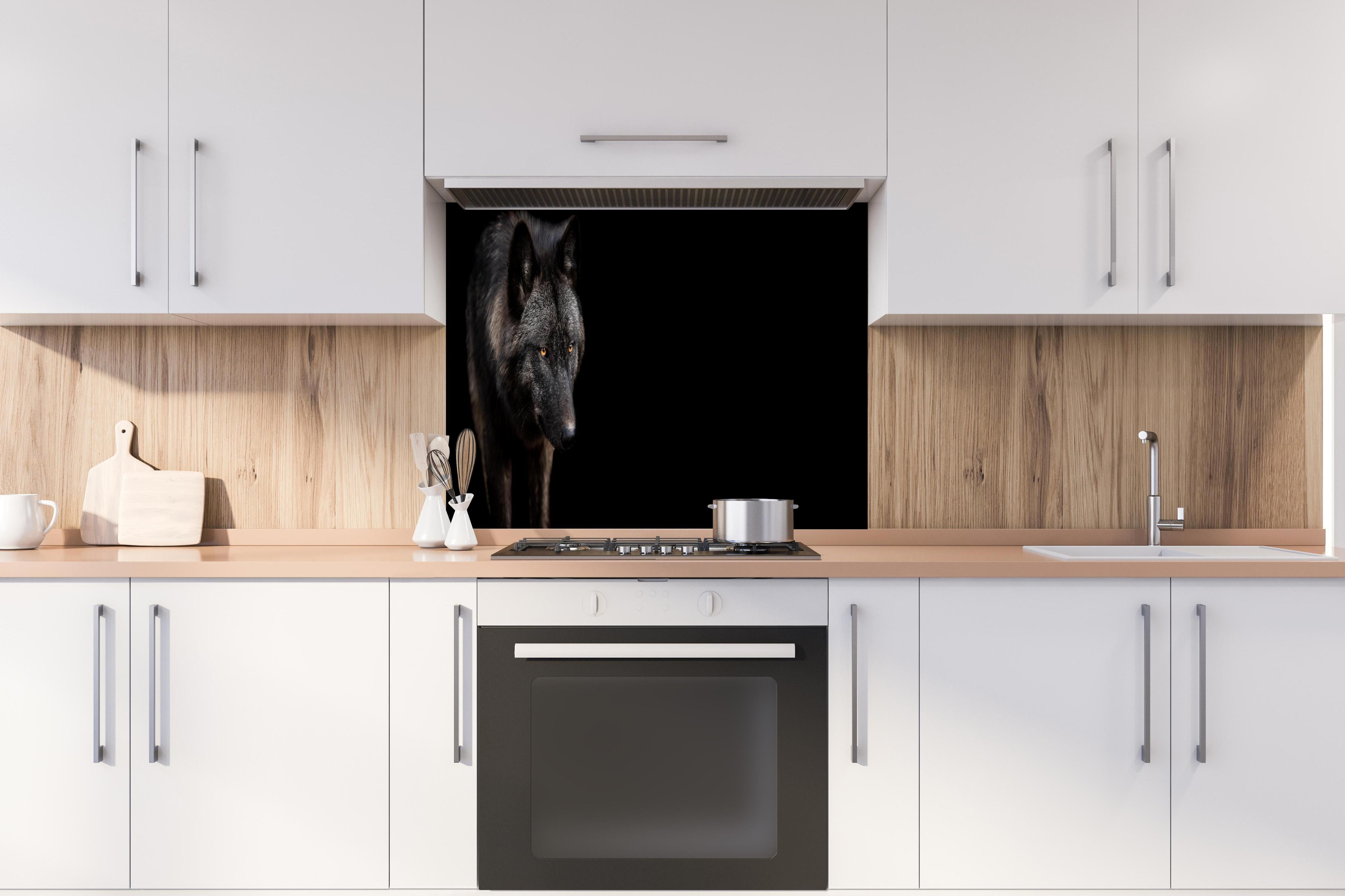 Spritzschutz - Schwarzer Wolf auf schwarzem Hintergrund hinter einem Cerankochfeld zwischen Holz-Kochutensilien