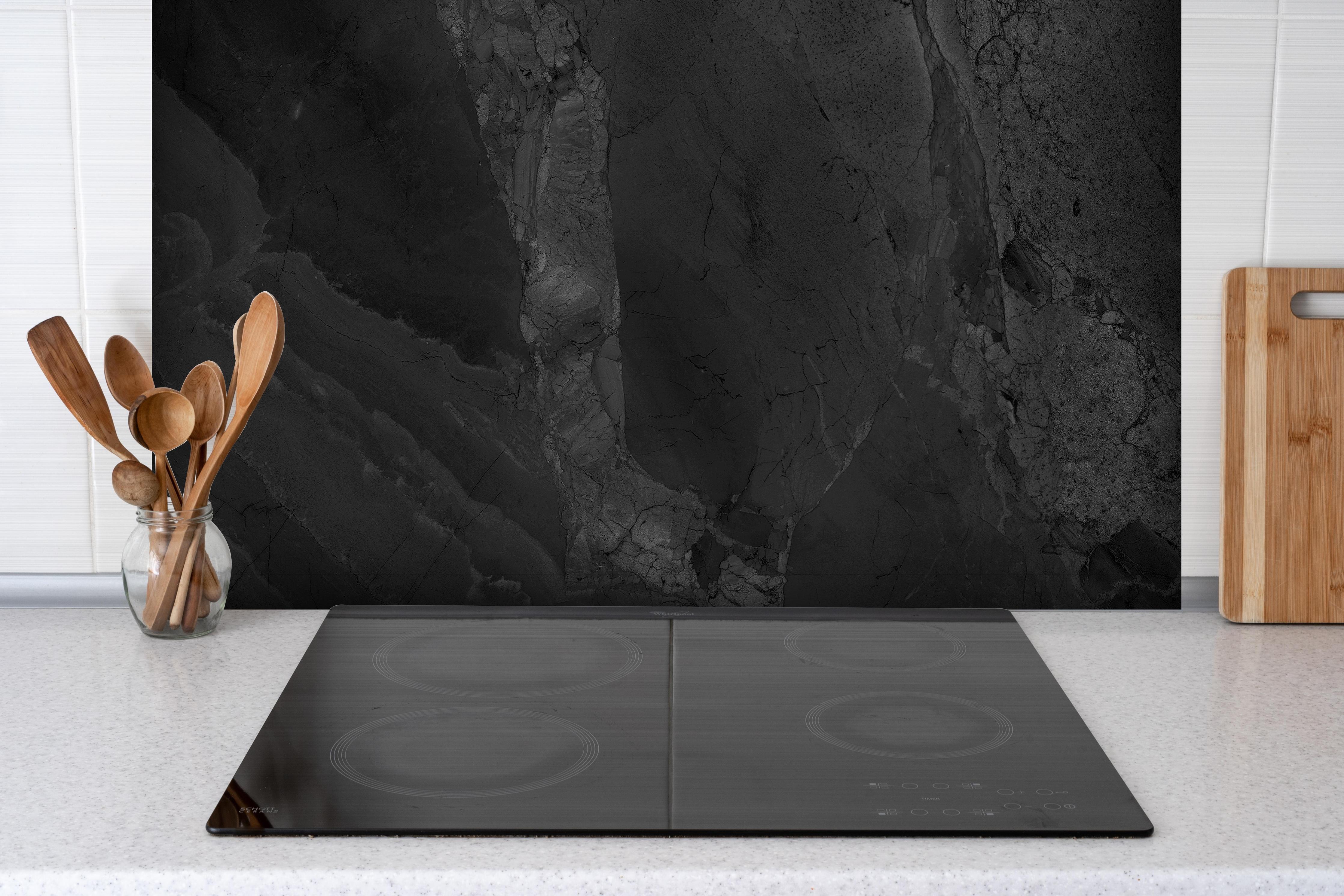 Spritzschutz - Schwarzer dunkler Marmor-Muster hinter einem Cerankochfeld zwischen Holz-Kochutensilien