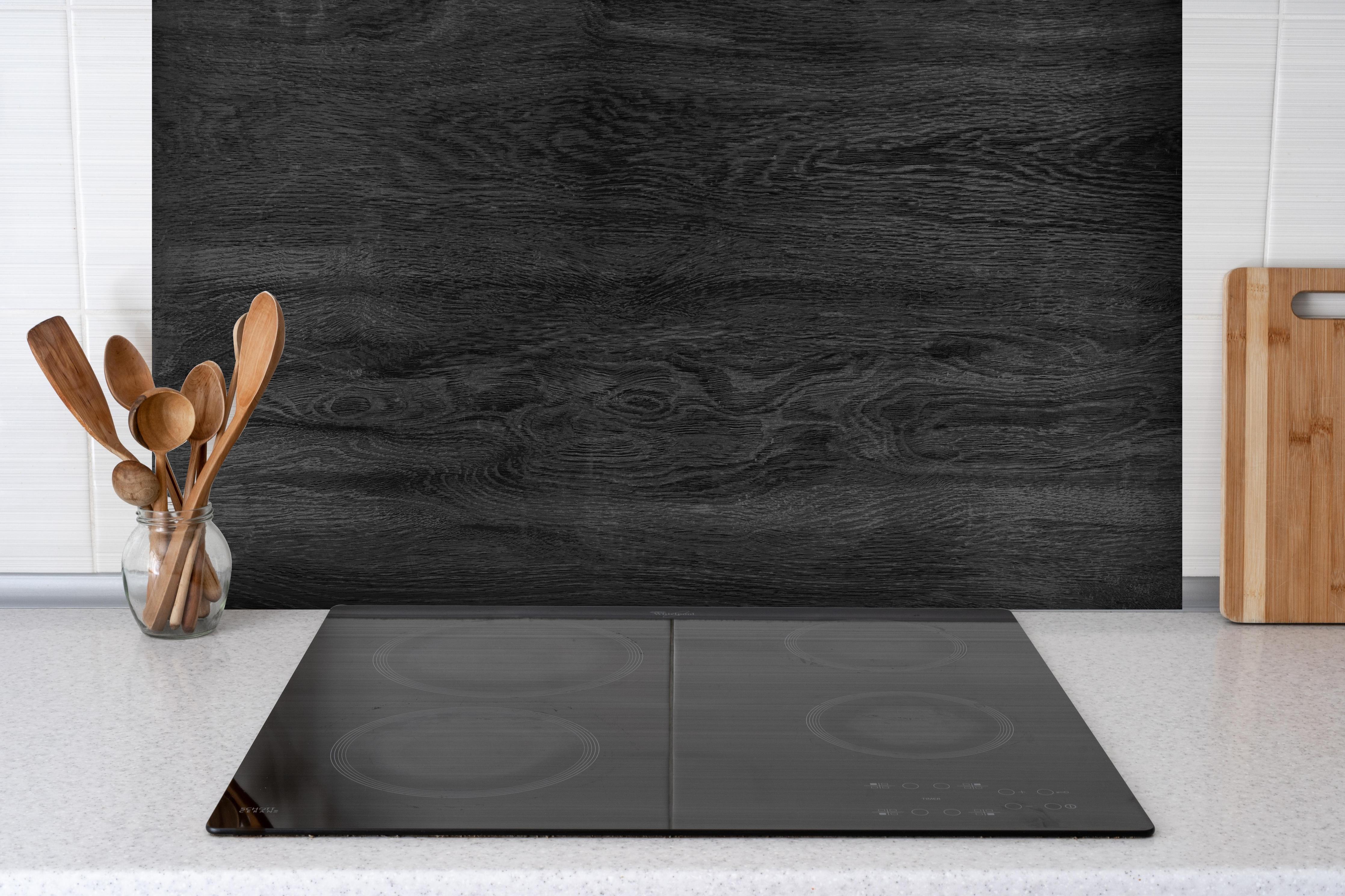 Spritzschutz - Schwarzes Holz Hintergrund hinter einem Cerankochfeld zwischen Holz-Kochutensilien