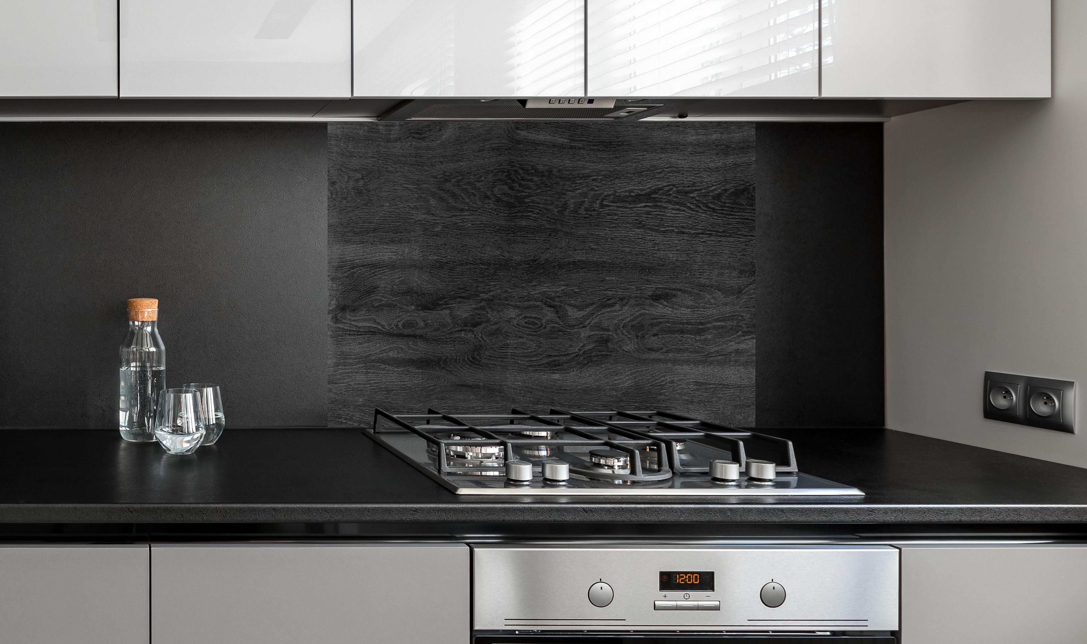 Spritzschutz - Schwarzes Holz Hintergrund hinter einem Cerankochfeld zwischen Holz-Kochutensilien