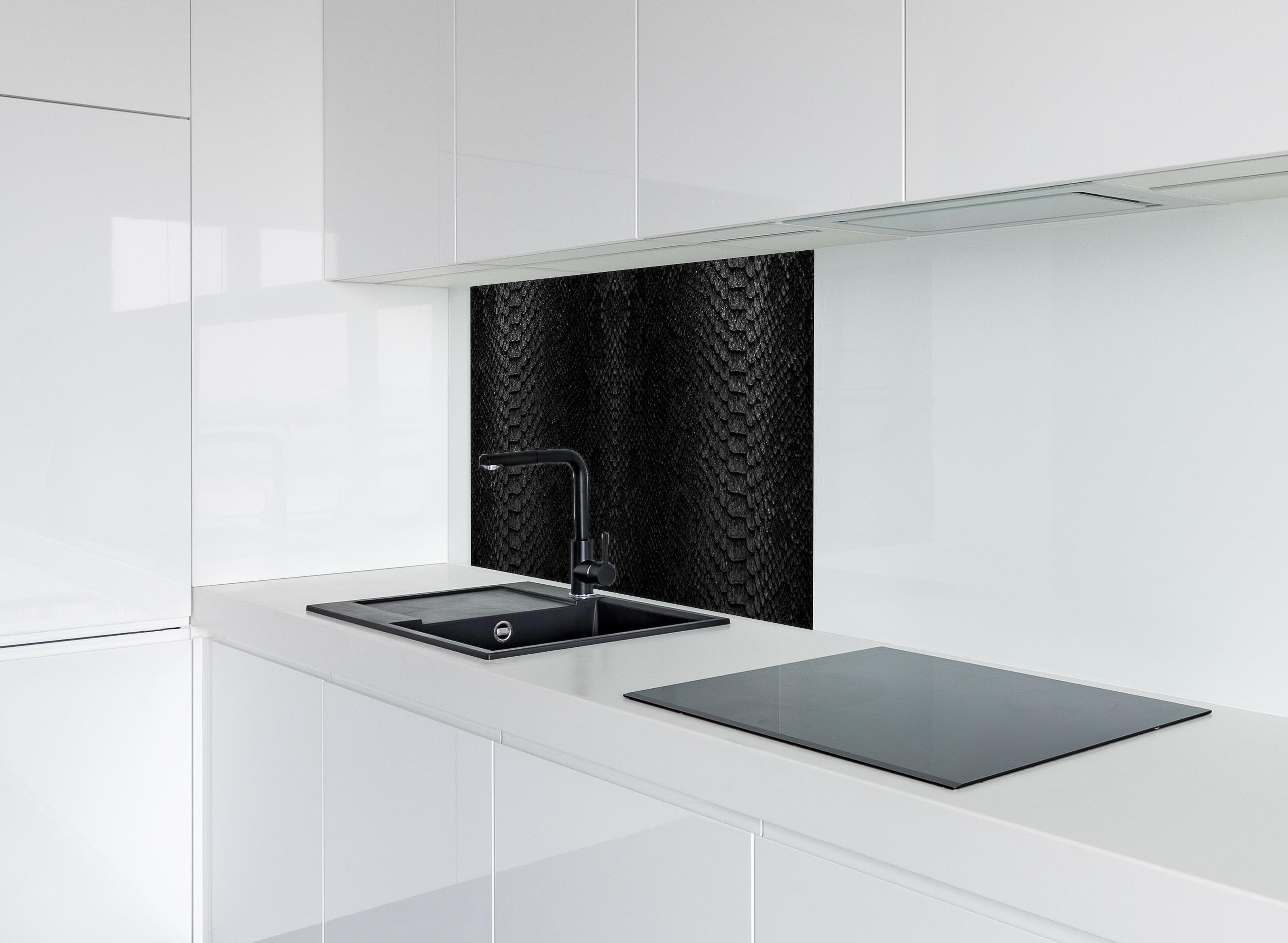 Spritzschutz - Schwarzes Schlangenhautmuster hinter einem Cerankochfeld zwischen Holz-Kochutensilien