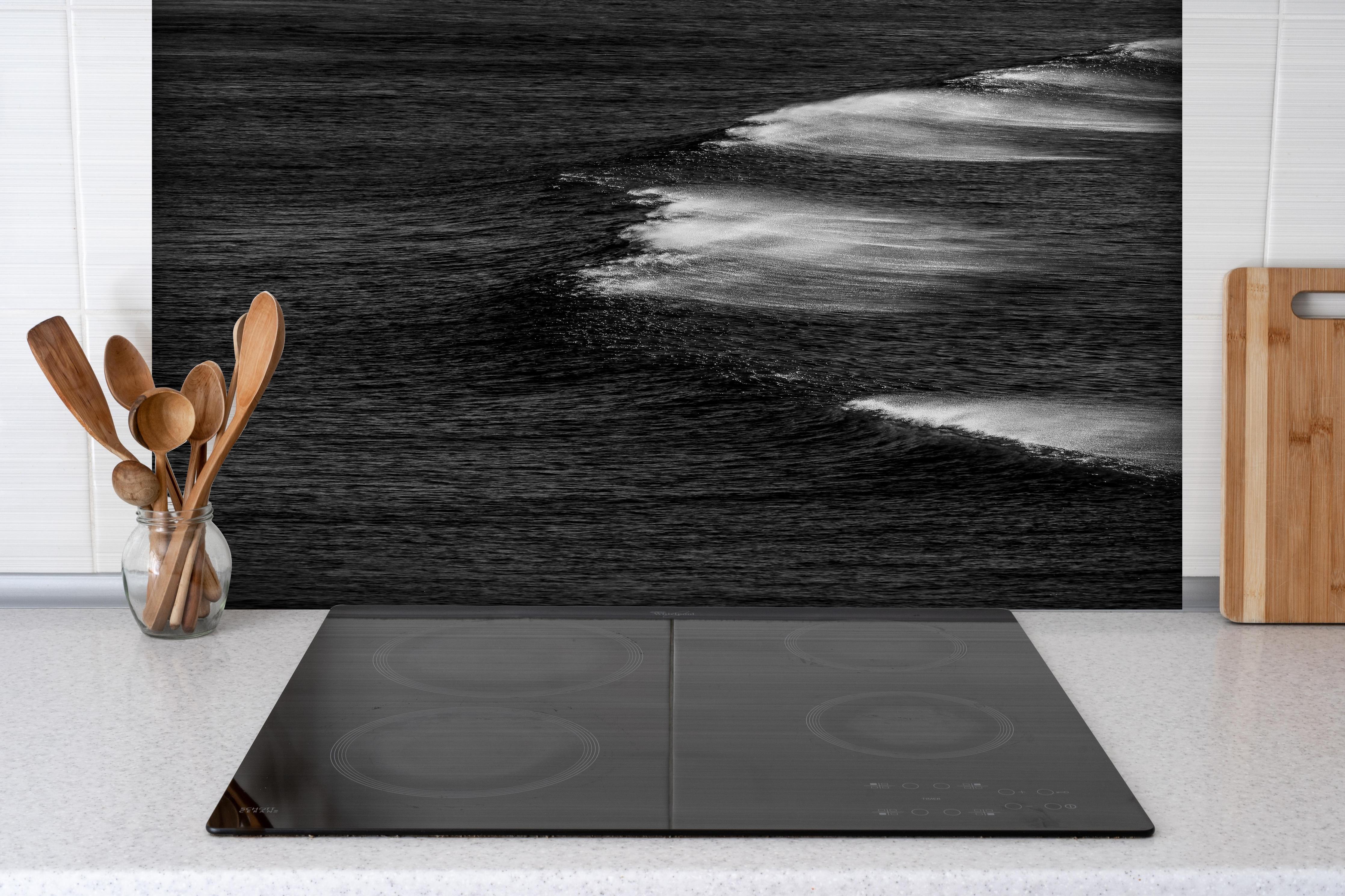 Spritzschutz - Schwarzweiße Ozeanwellen aus der Vogelperspektive hinter einem Cerankochfeld zwischen Holz-Kochutensilien