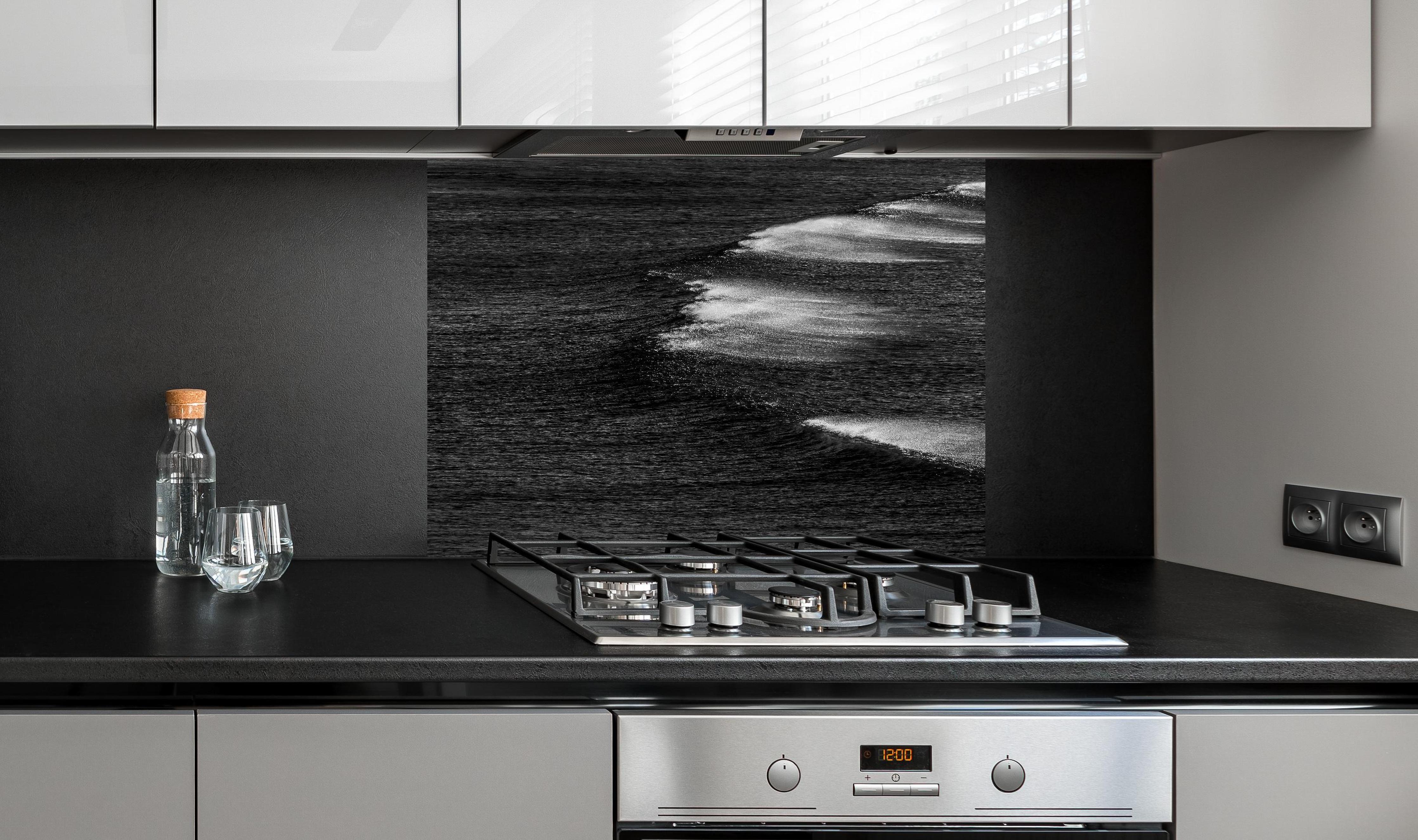 Spritzschutz - Schwarzweiße Ozeanwellen aus der Vogelperspektive hinter einem Cerankochfeld zwischen Holz-Kochutensilien