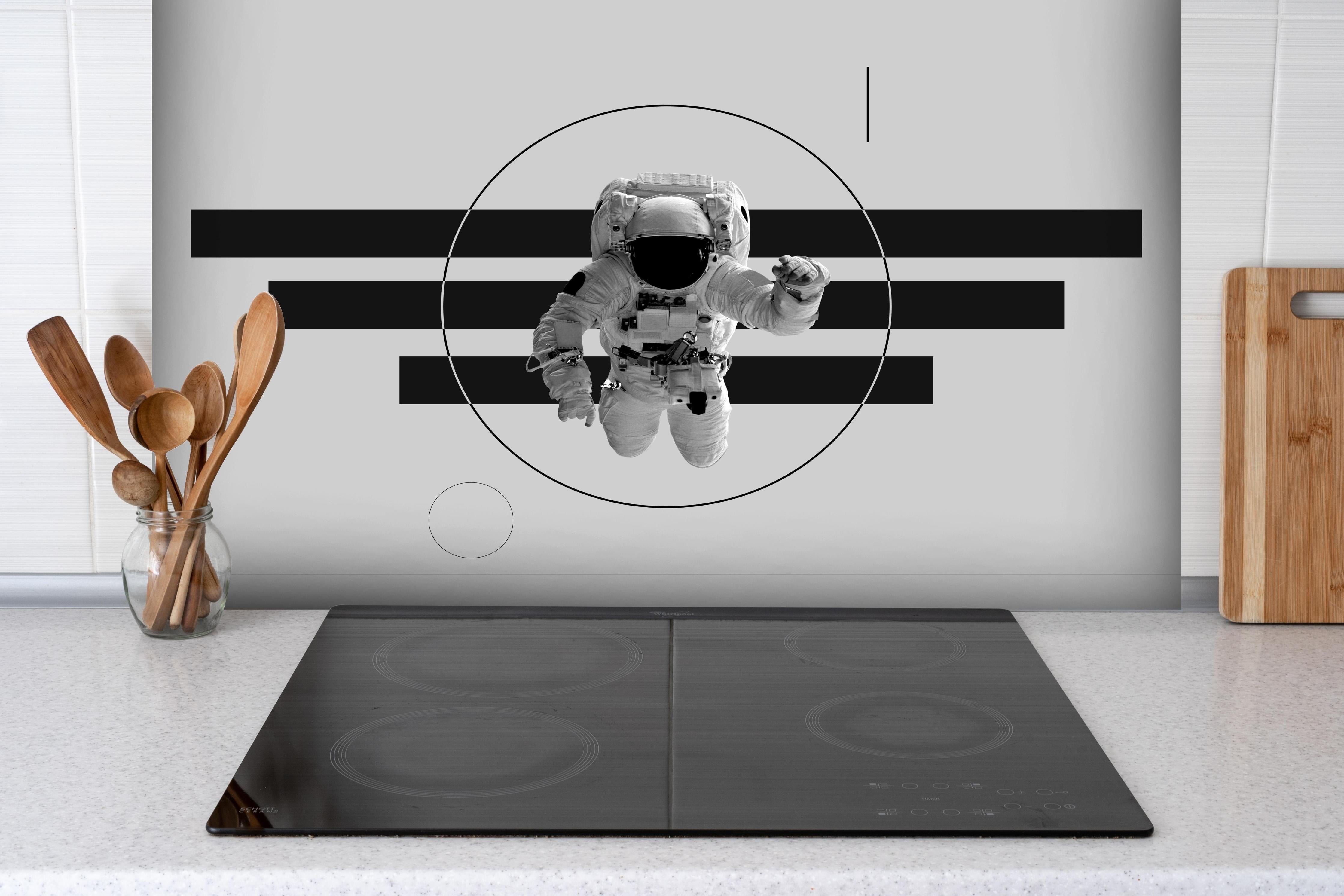 Spritzschutz - Schwebender Astronaut, Grau-Schwarzes Design hinter einem Cerankochfeld zwischen Holz-Kochutensilien