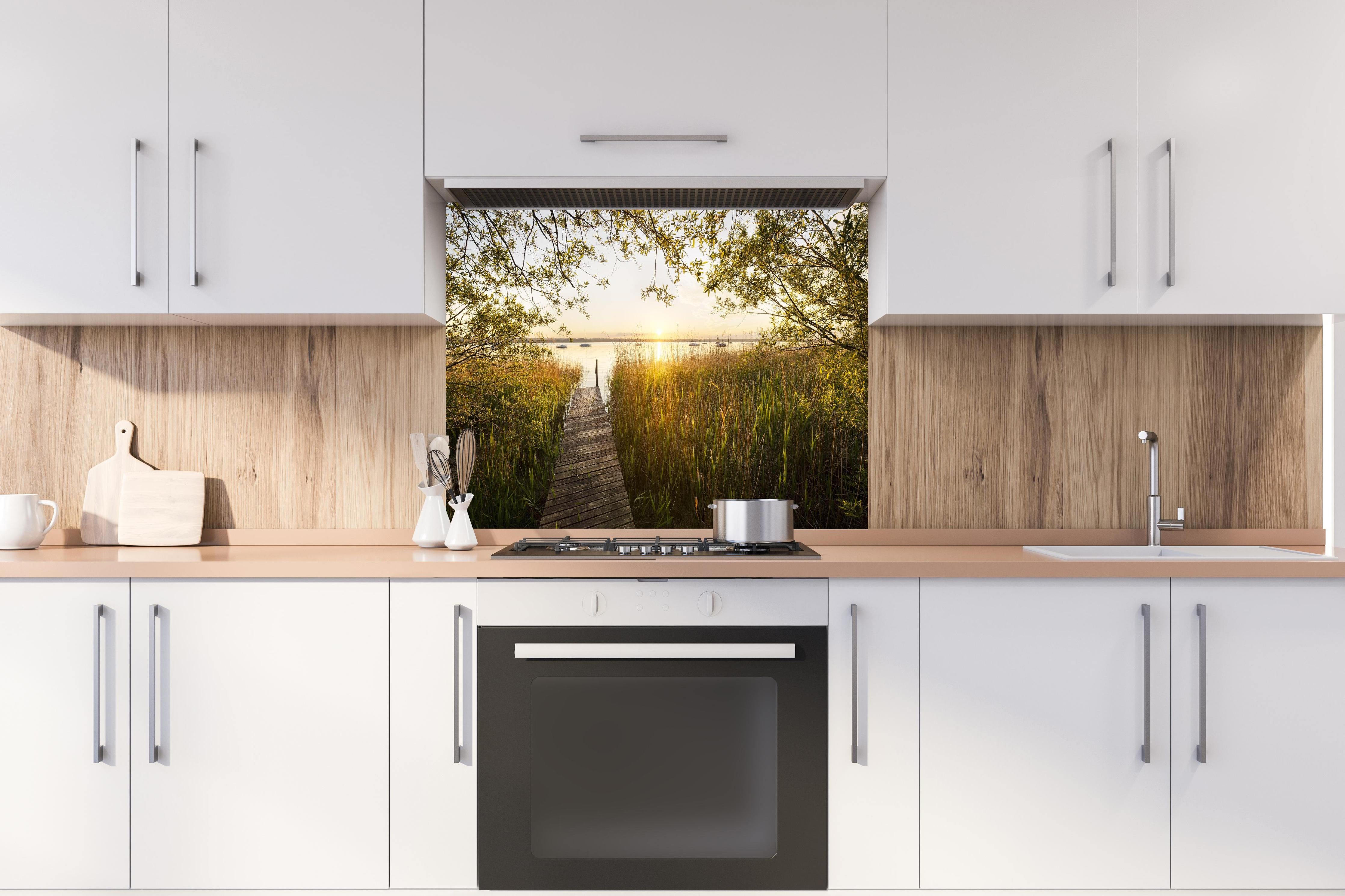 Spritzschutz - See in Bayern bei Sonnenuntergang hinter einem Cerankochfeld zwischen Holz-Kochutensilien