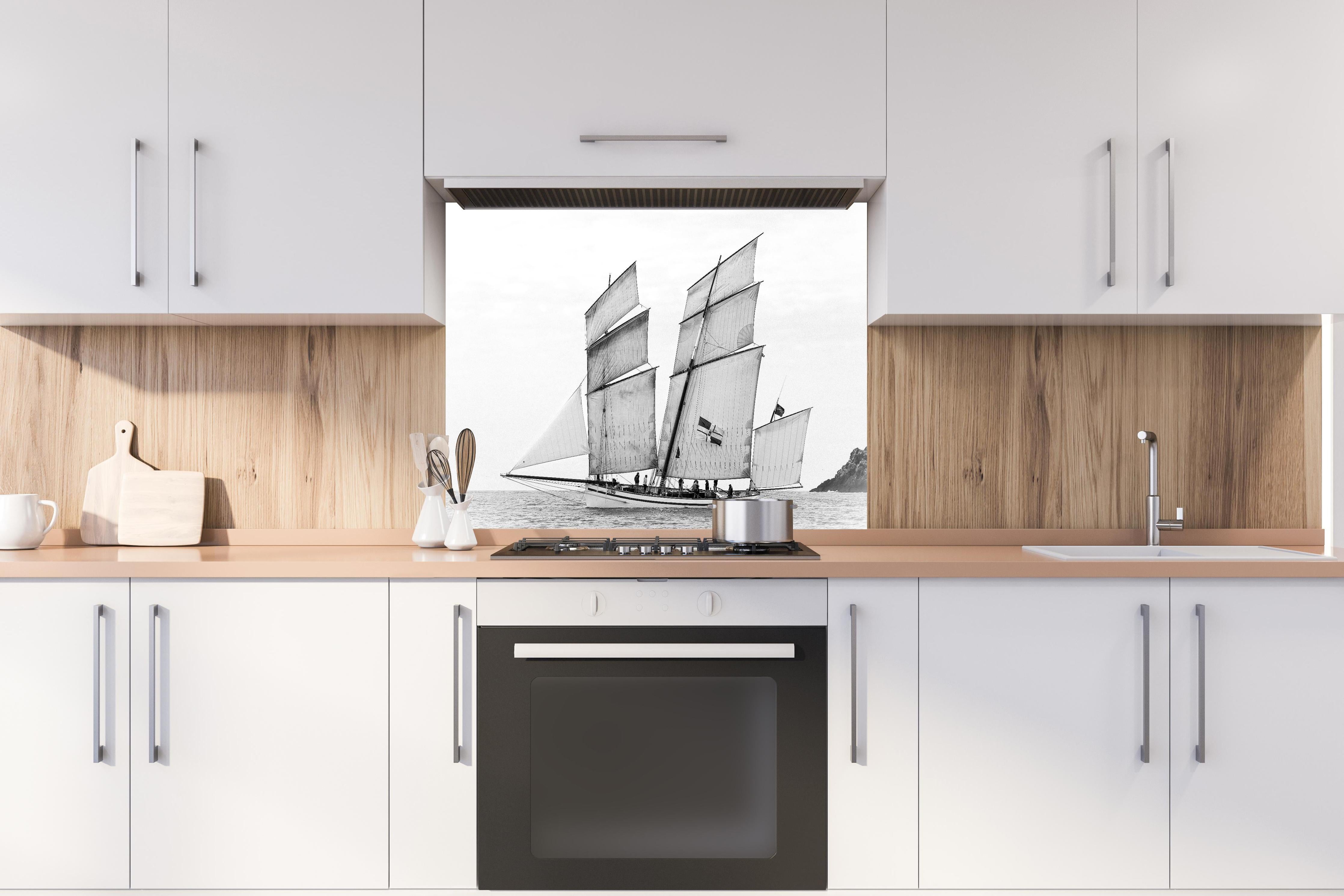 Spritzschutz - Segelboot auf dem Meer hinter einem Cerankochfeld zwischen Holz-Kochutensilien