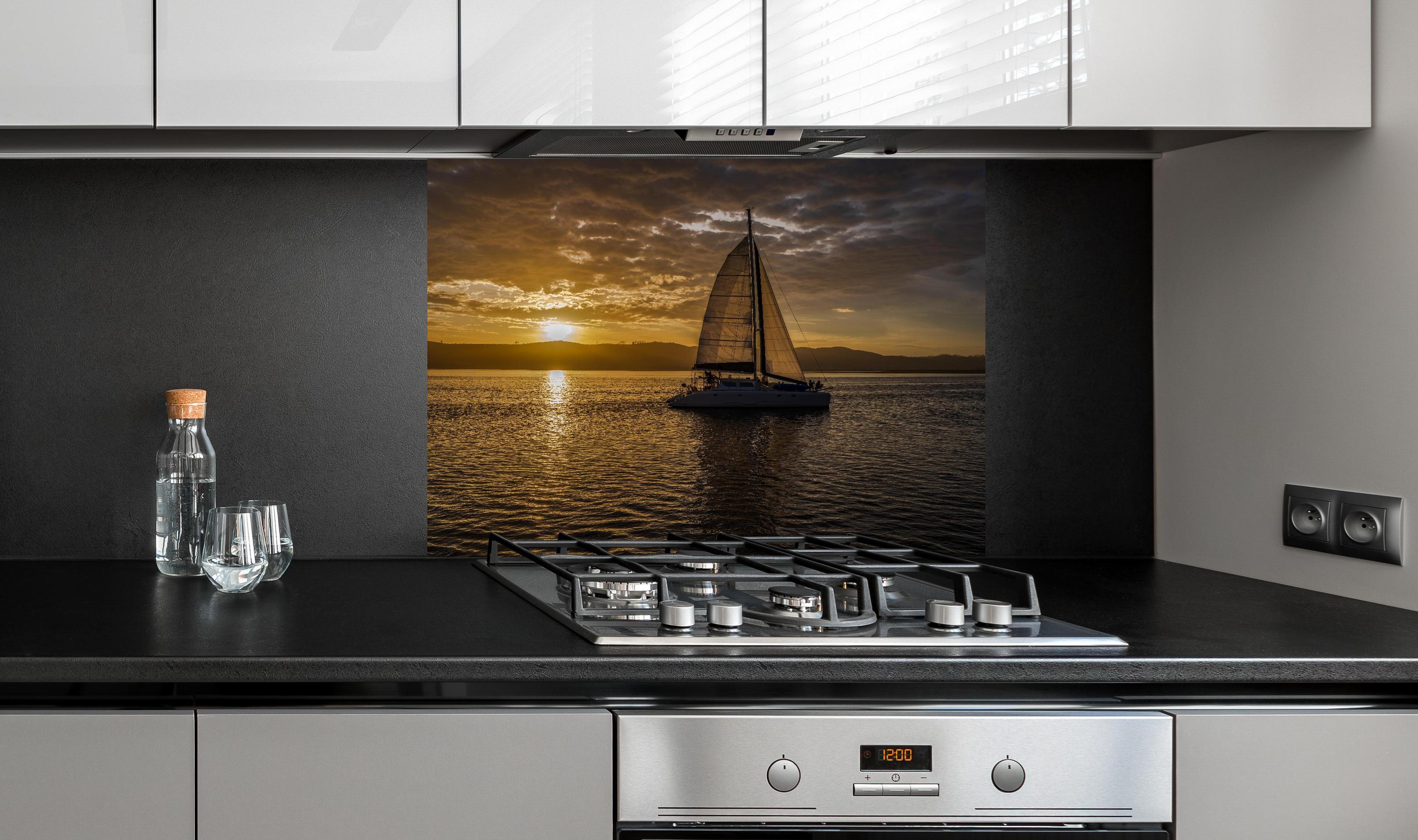 Spritzschutz - Segelboot bei Sonnenuntergang in der Lagune von Knysna hinter einem Cerankochfeld zwischen Holz-Kochutensilien