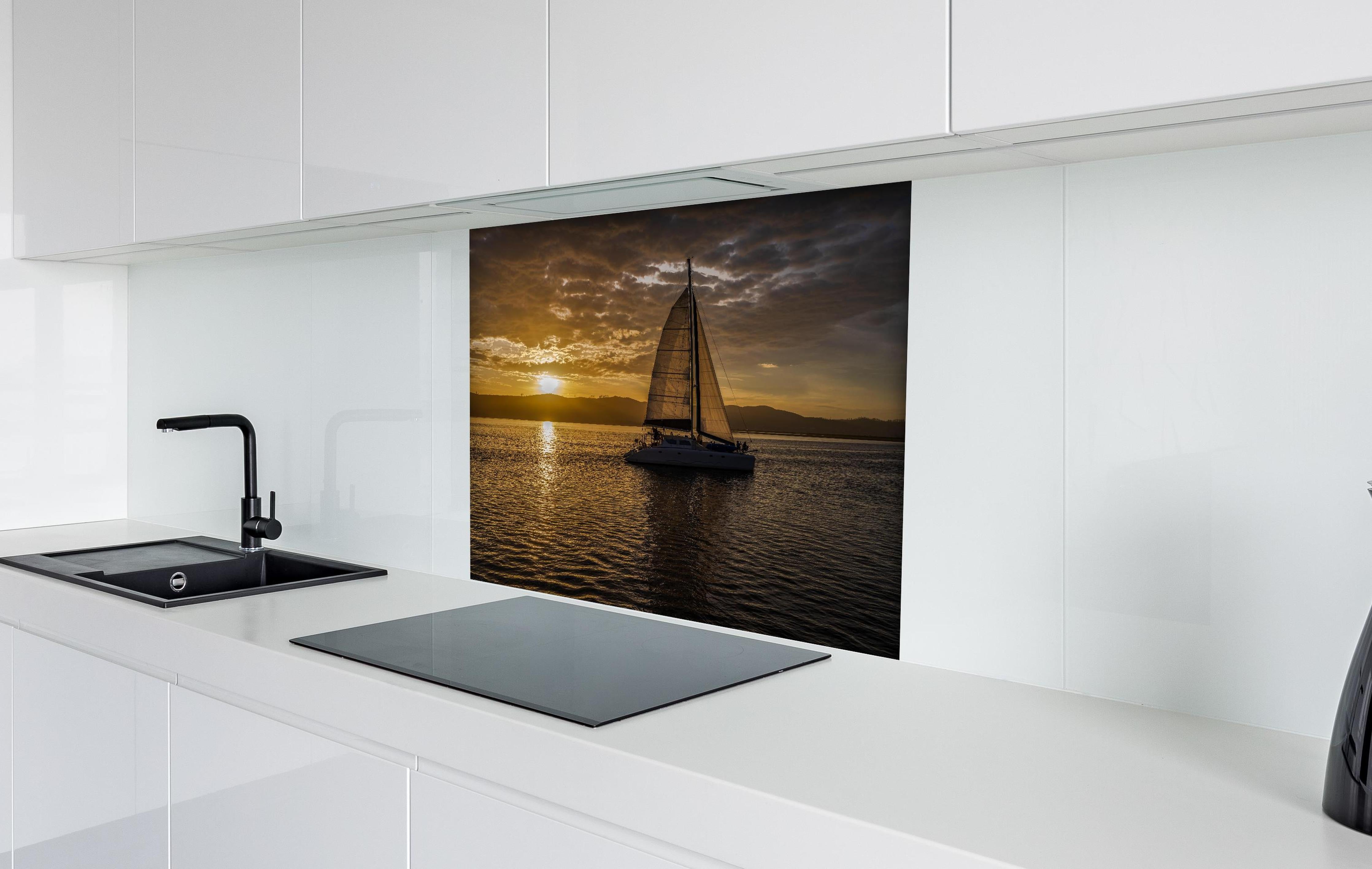 Spritzschutz - Segelboot bei Sonnenuntergang in der Lagune von Knysna hinter einem Cerankochfeld zwischen Holz-Kochutensilien