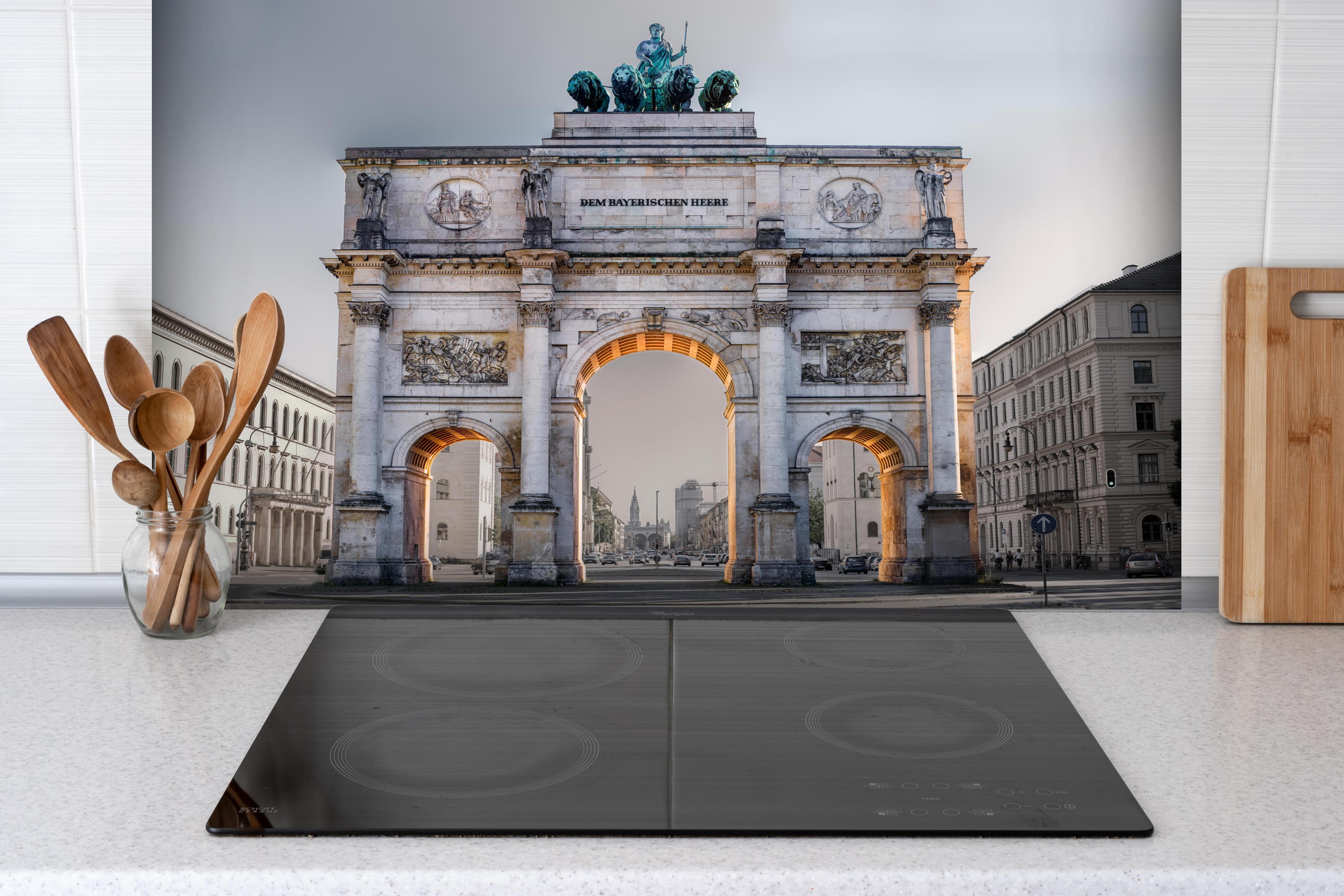 Spritzschutz - Siegestor in München an der Leopoldstraße hinter einem Cerankochfeld zwischen Holz-Kochutensilien