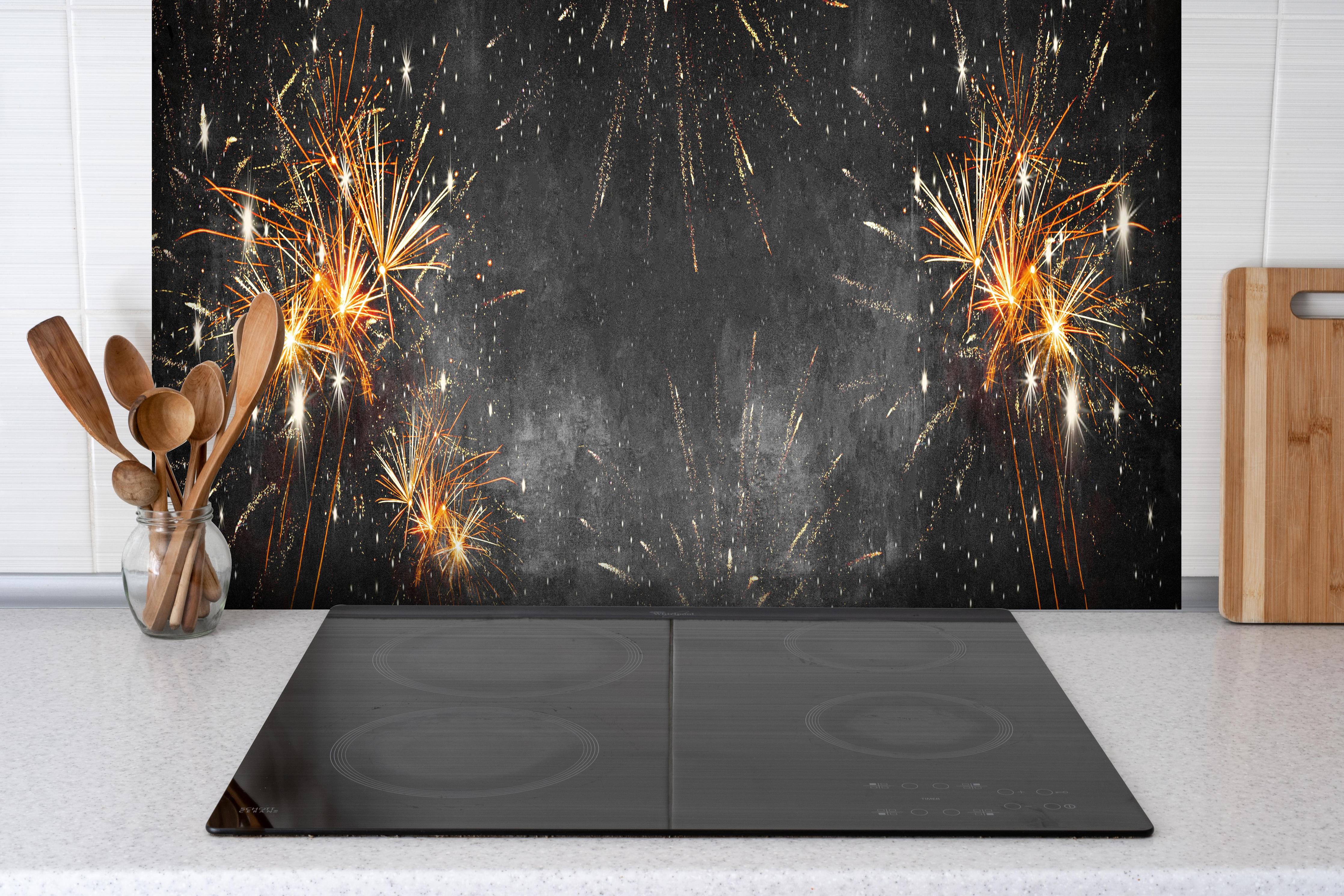 Spritzschutz - Silvesterparty Feuerwerk auf Grauschwarz hinter einem Cerankochfeld zwischen Holz-Kochutensilien