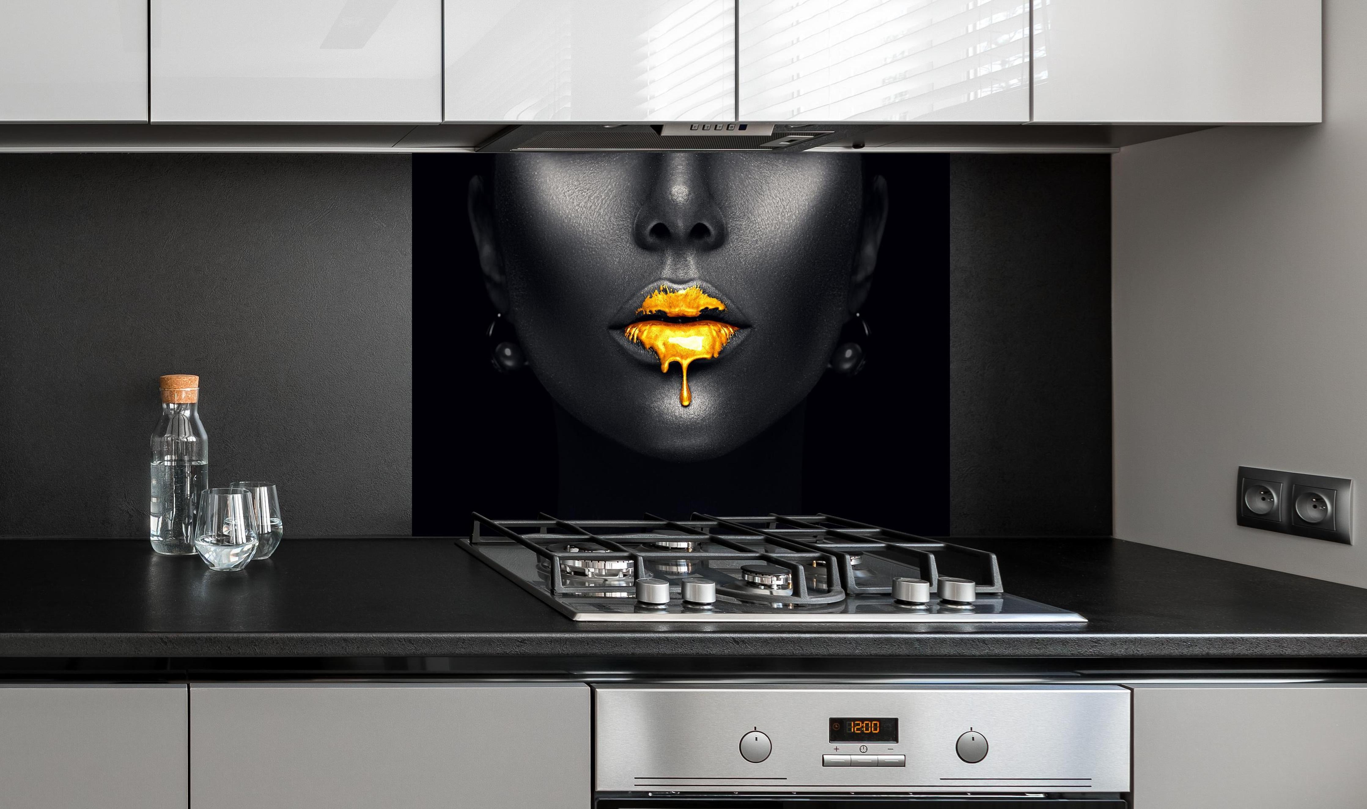 Spritzschutz - Sinnliche Lippen mit Goldtropfen hinter einem Cerankochfeld zwischen Holz-Kochutensilien