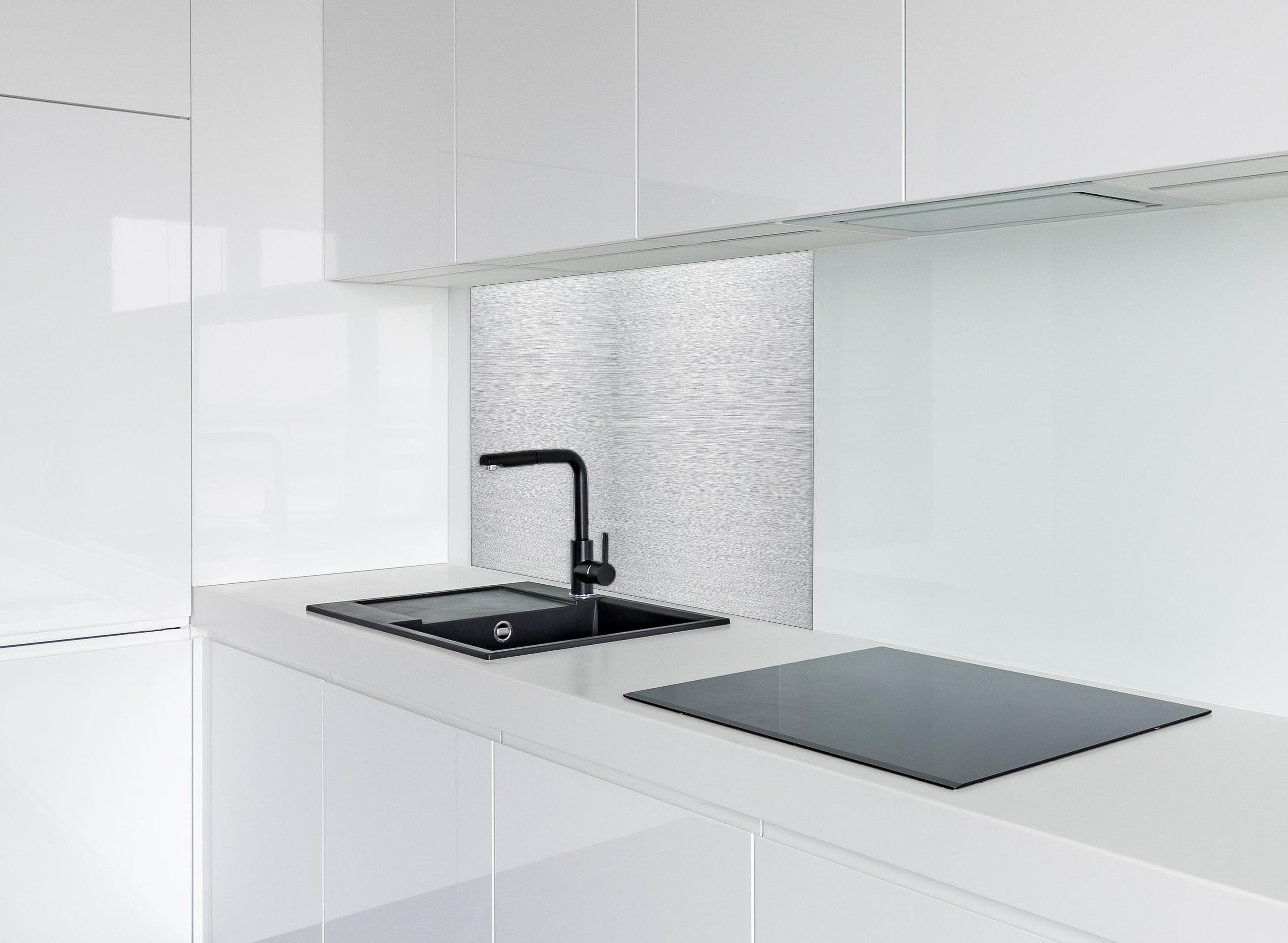 Spritzschutz - Skip hinter einem Cerankochfeld zwischen Holz-Kochutensilien