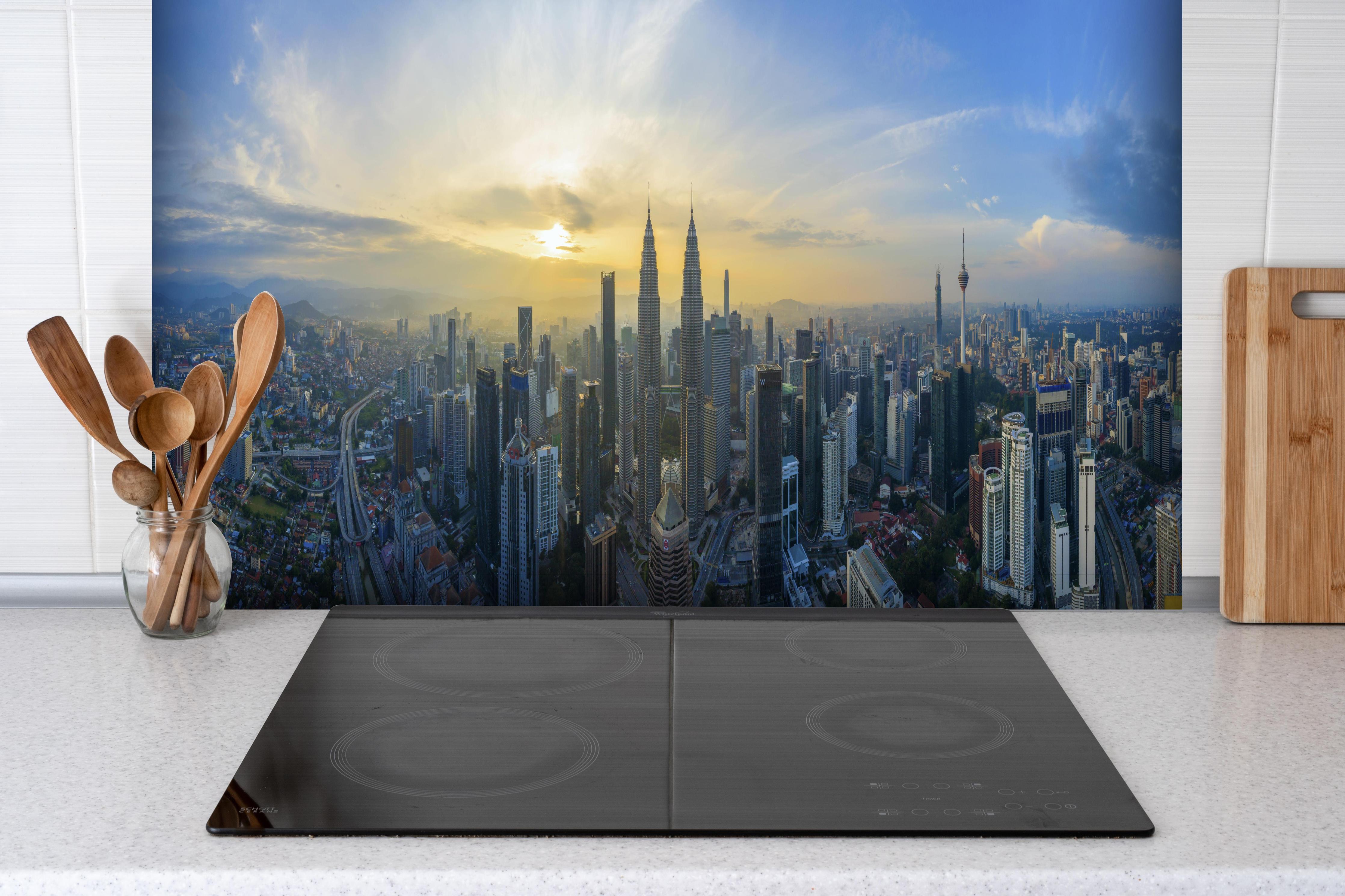 Spritzschutz - Skyline Kuala Lumpur City hinter einem Cerankochfeld zwischen Holz-Kochutensilien