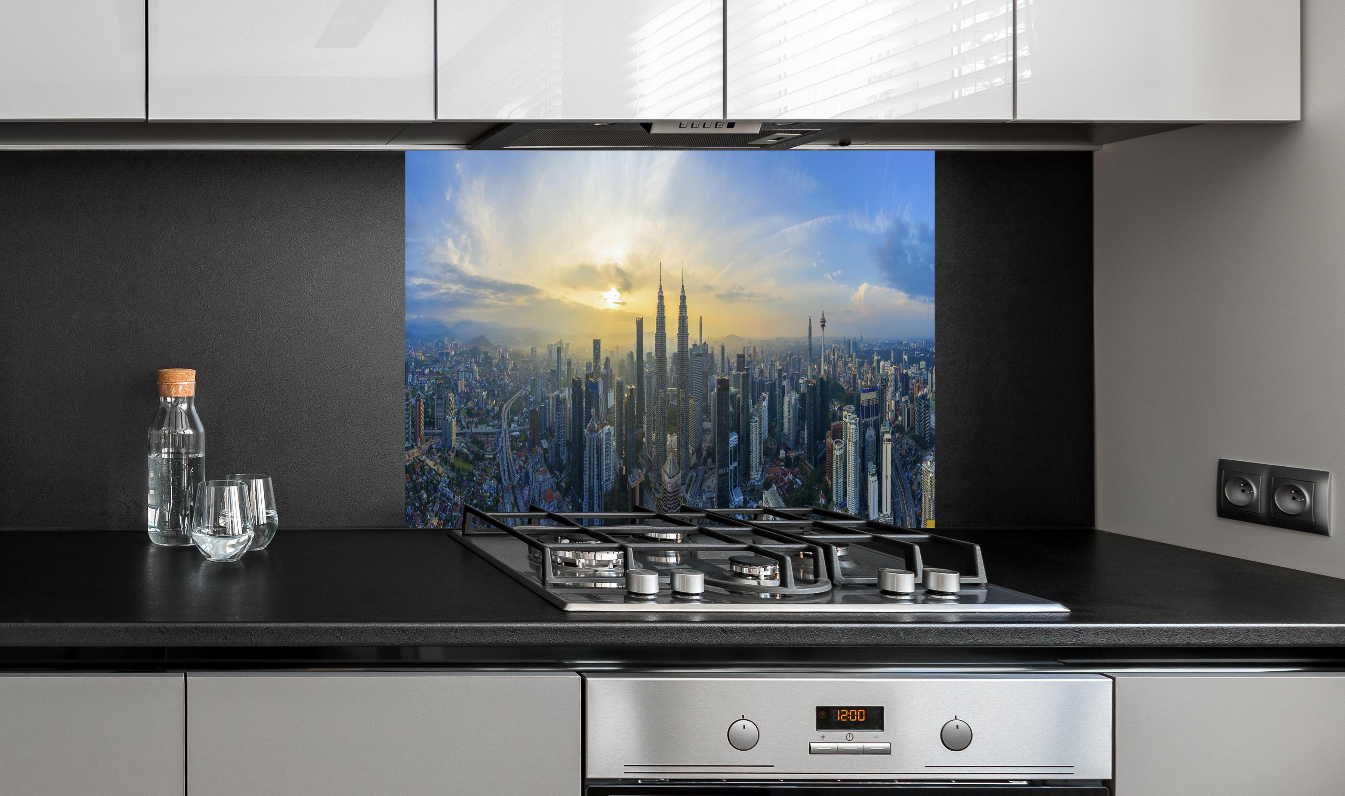 Spritzschutz - Skyline Kuala Lumpur City hinter einem Cerankochfeld zwischen Holz-Kochutensilien
