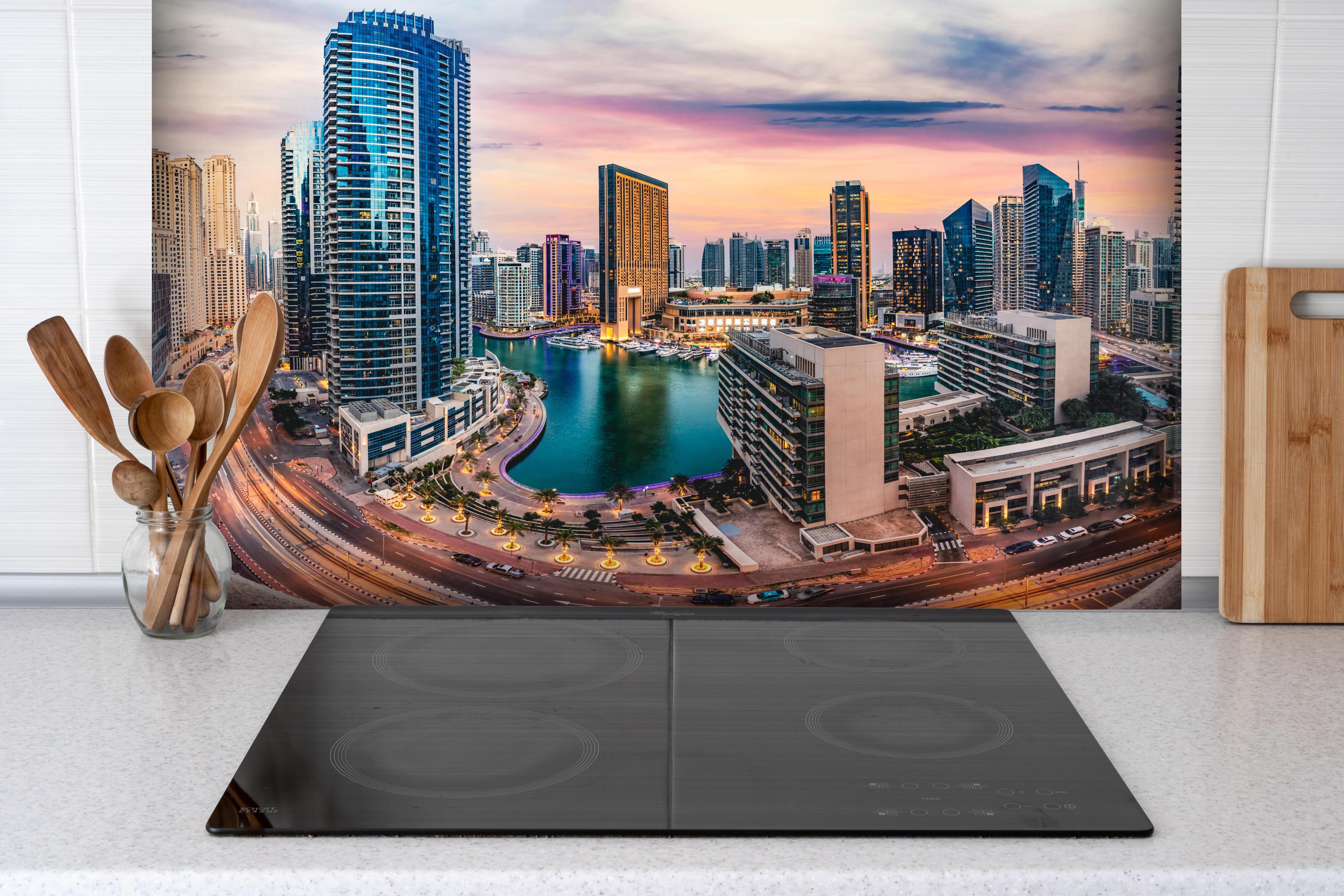 Spritzschutz - Skyline des Jachthafens von Dubai bei Sonnenuntergang hinter einem Cerankochfeld zwischen Holz-Kochutensilien