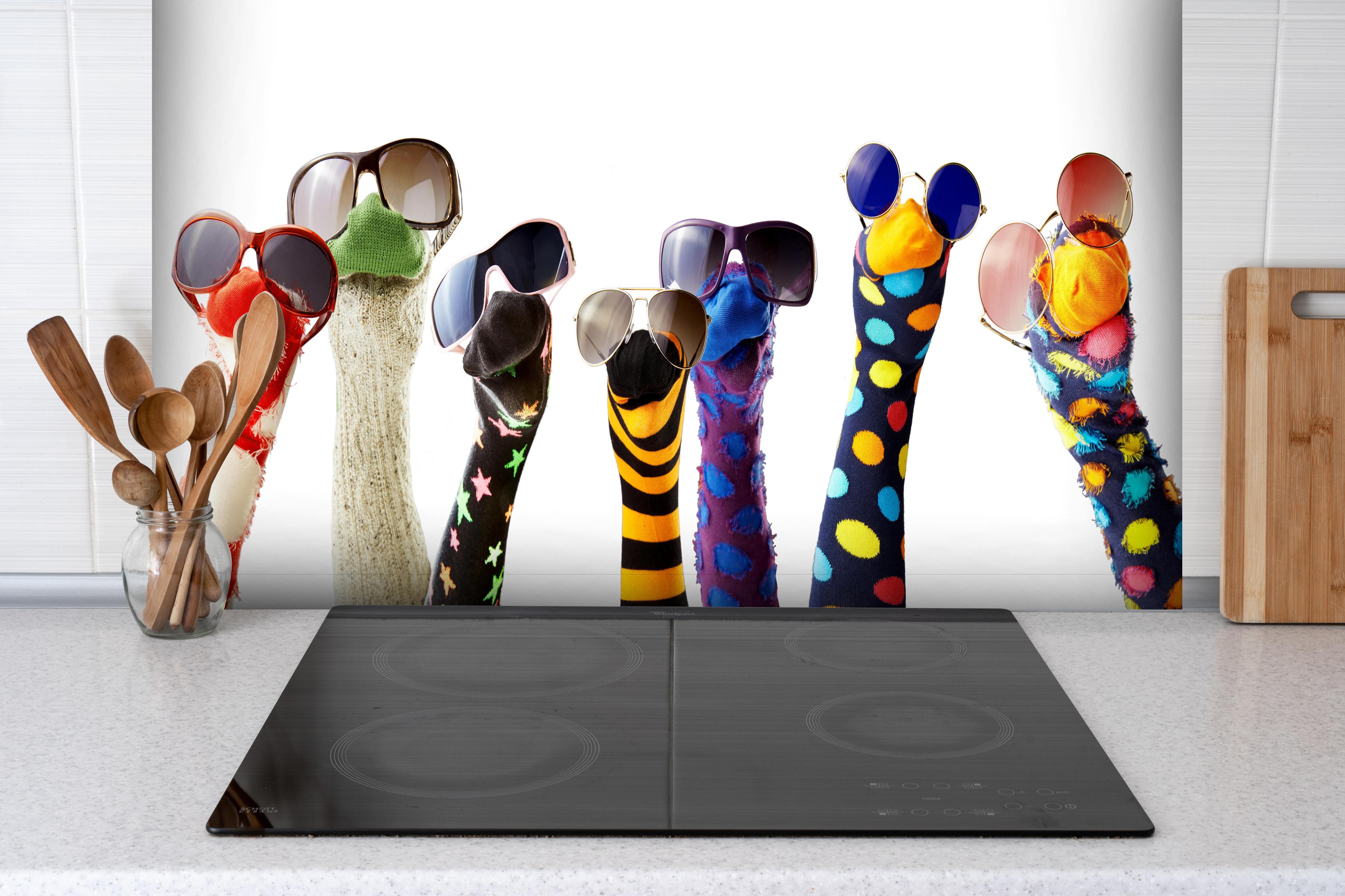 Spritzschutz - Sockenpuppen mit Brille hinter einem Cerankochfeld zwischen Holz-Kochutensilien