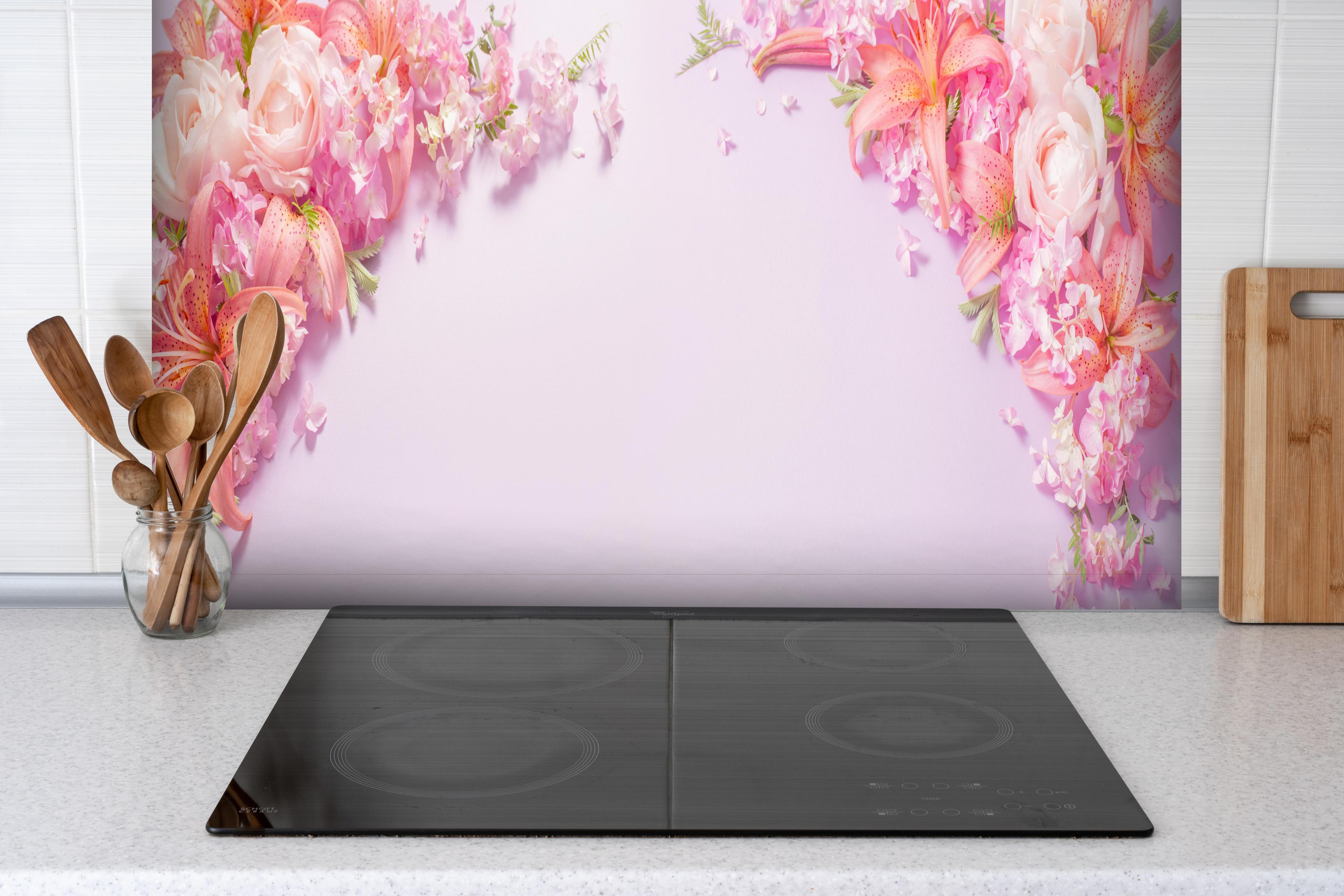 Spritzschutz - Sommerliche Blumenarrangements auf Papier hinter einem Cerankochfeld zwischen Holz-Kochutensilien