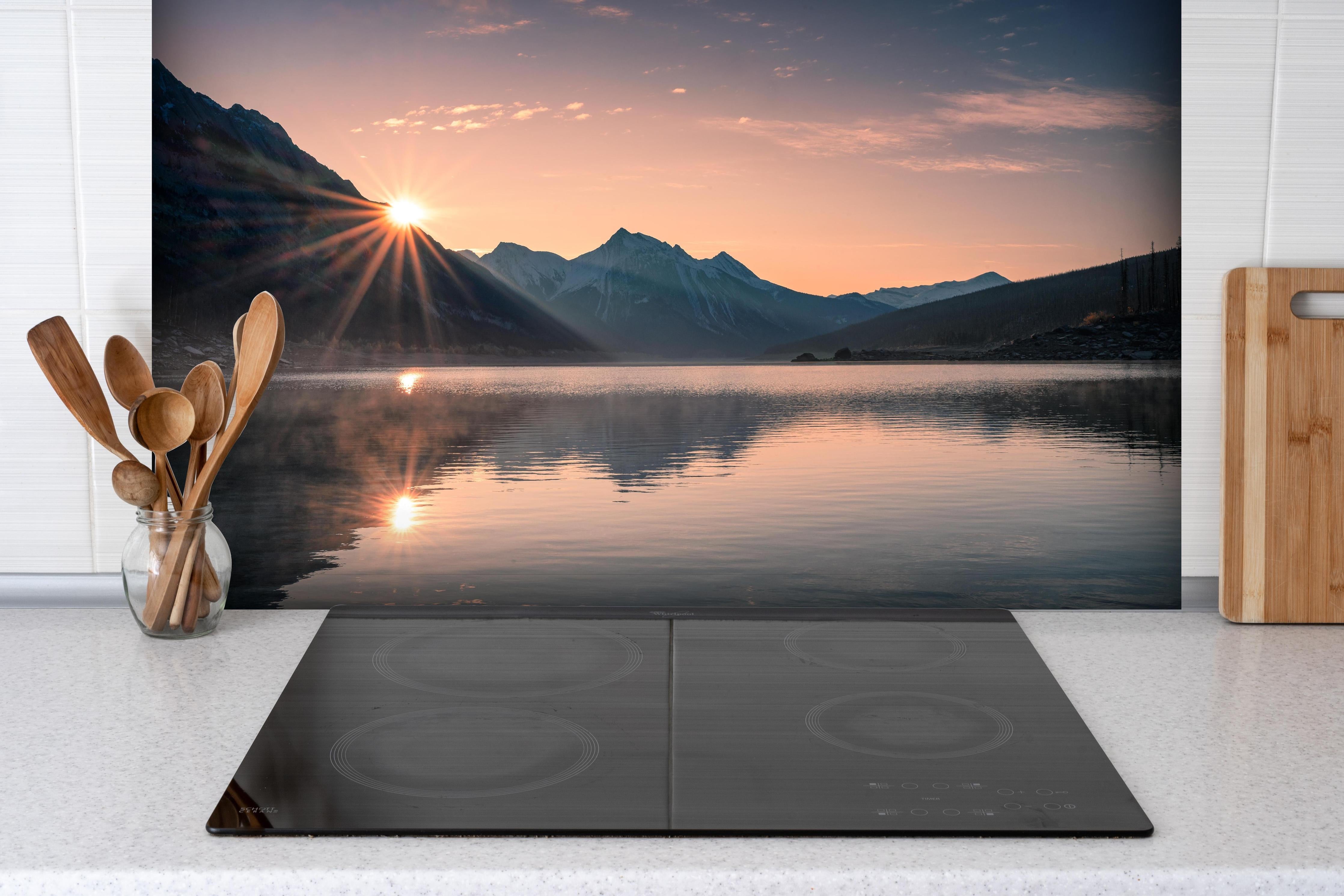 Spritzschutz - Sonnenaufgang Berge mit Nebelspiel hinter einem Cerankochfeld zwischen Holz-Kochutensilien