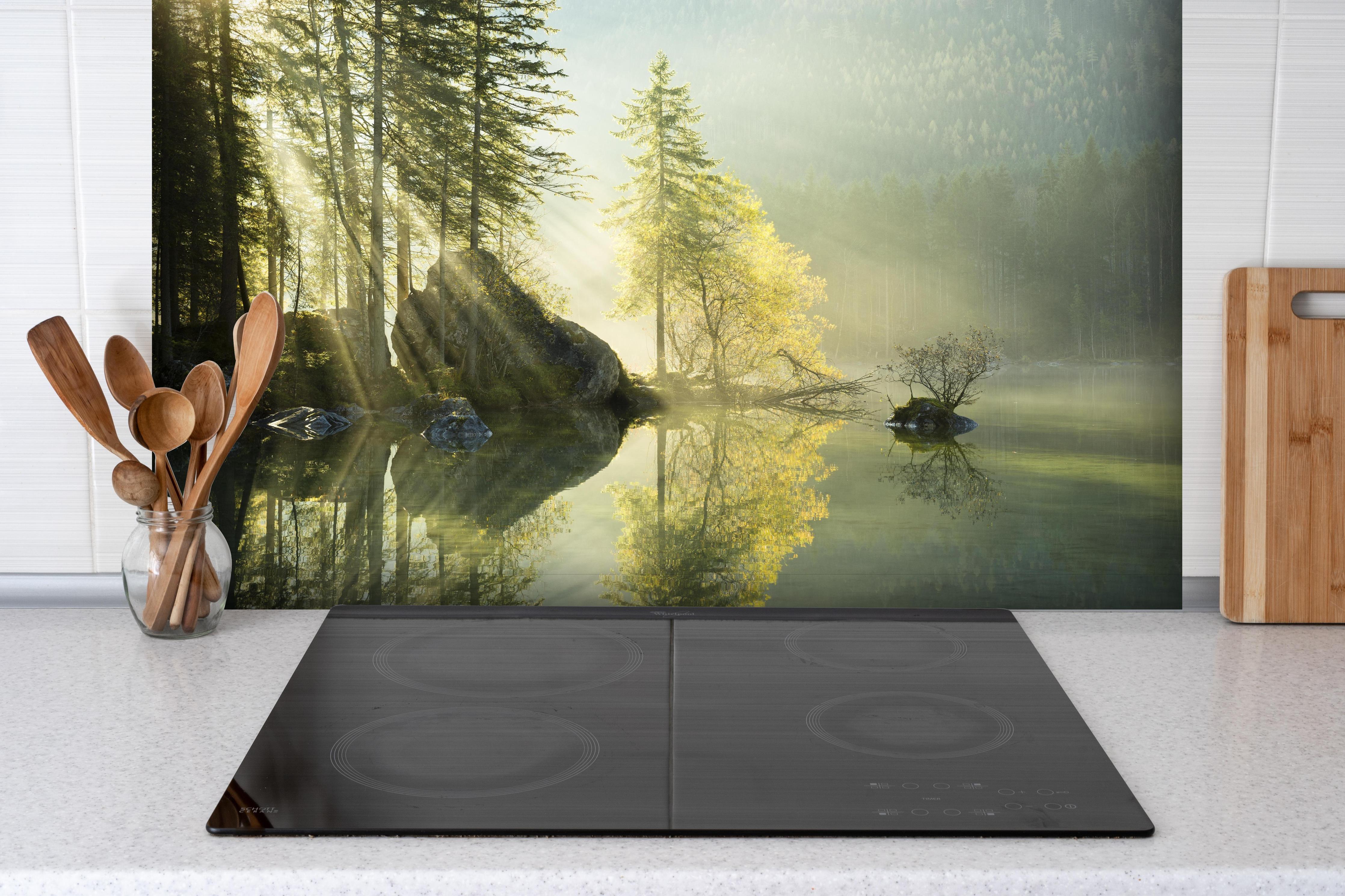 Spritzschutz - Sonnenstrahlen im See hinter einem Cerankochfeld zwischen Holz-Kochutensilien