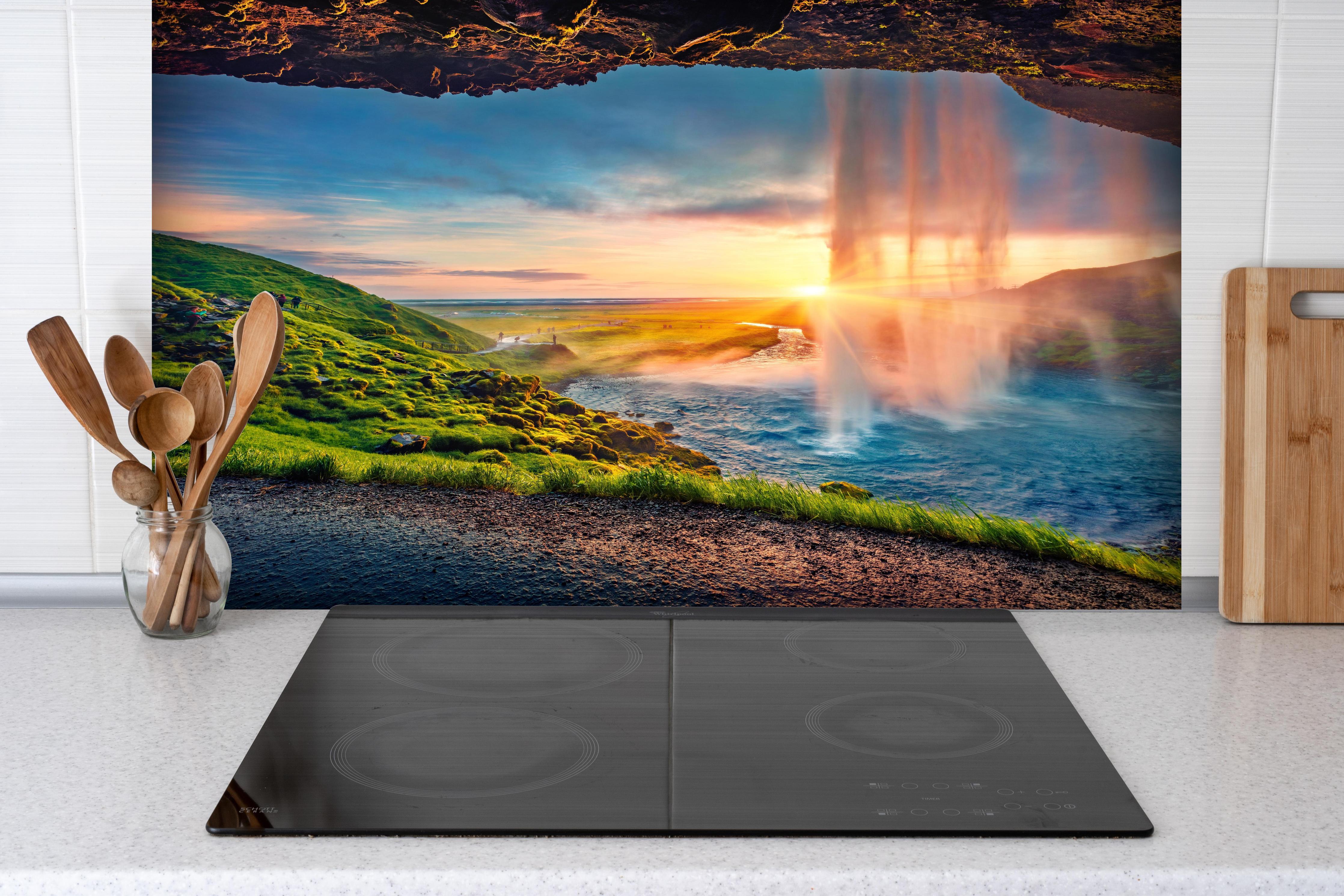 Spritzschutz - Spektakulärer Sonnenuntergang am Wasserfall Seljalandsfoss hinter einem Cerankochfeld zwischen Holz-Kochutensilien