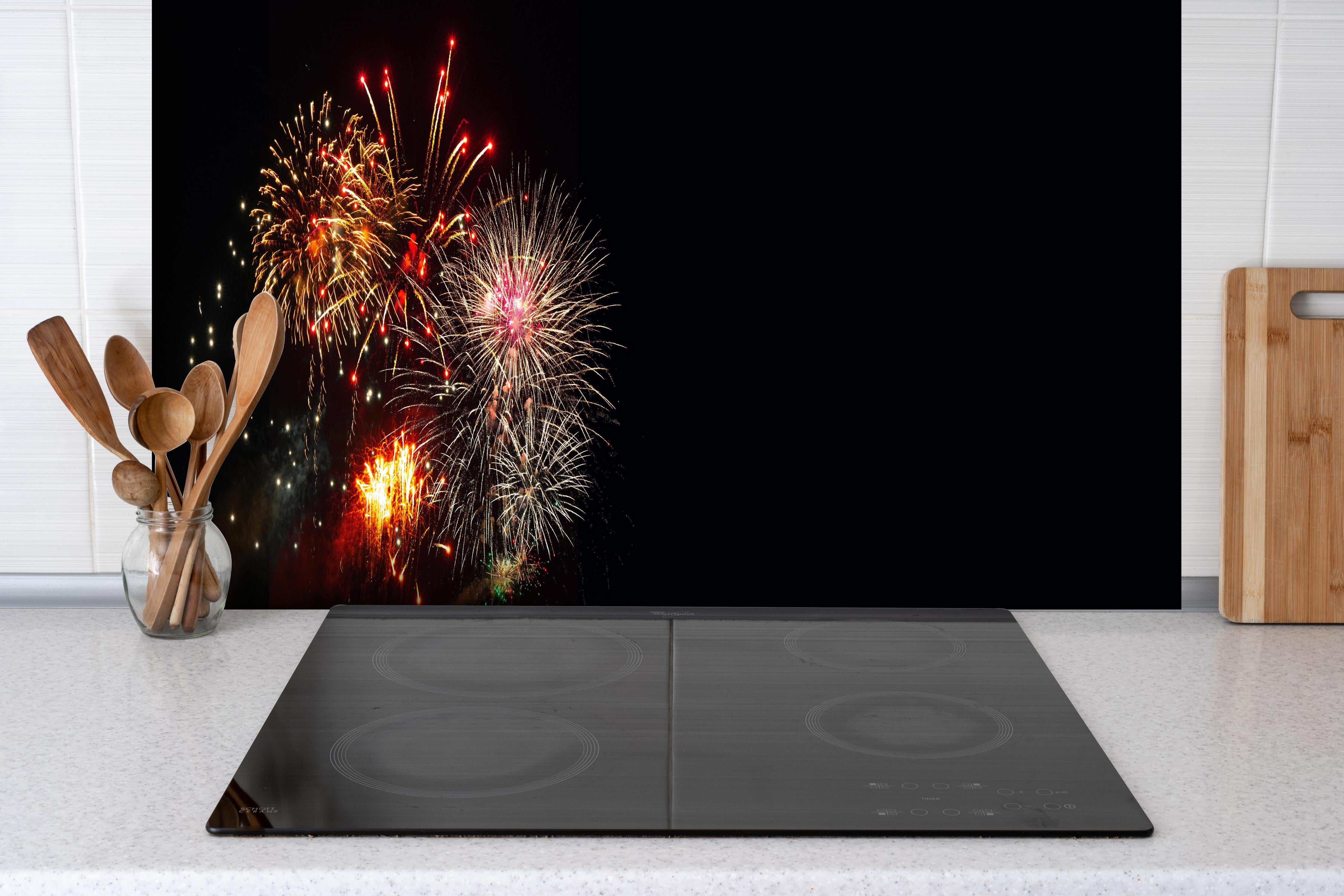 Spritzschutz - Spektakuläres Neujahrsfeuerwerk in Nacht hinter einem Cerankochfeld zwischen Holz-Kochutensilien
