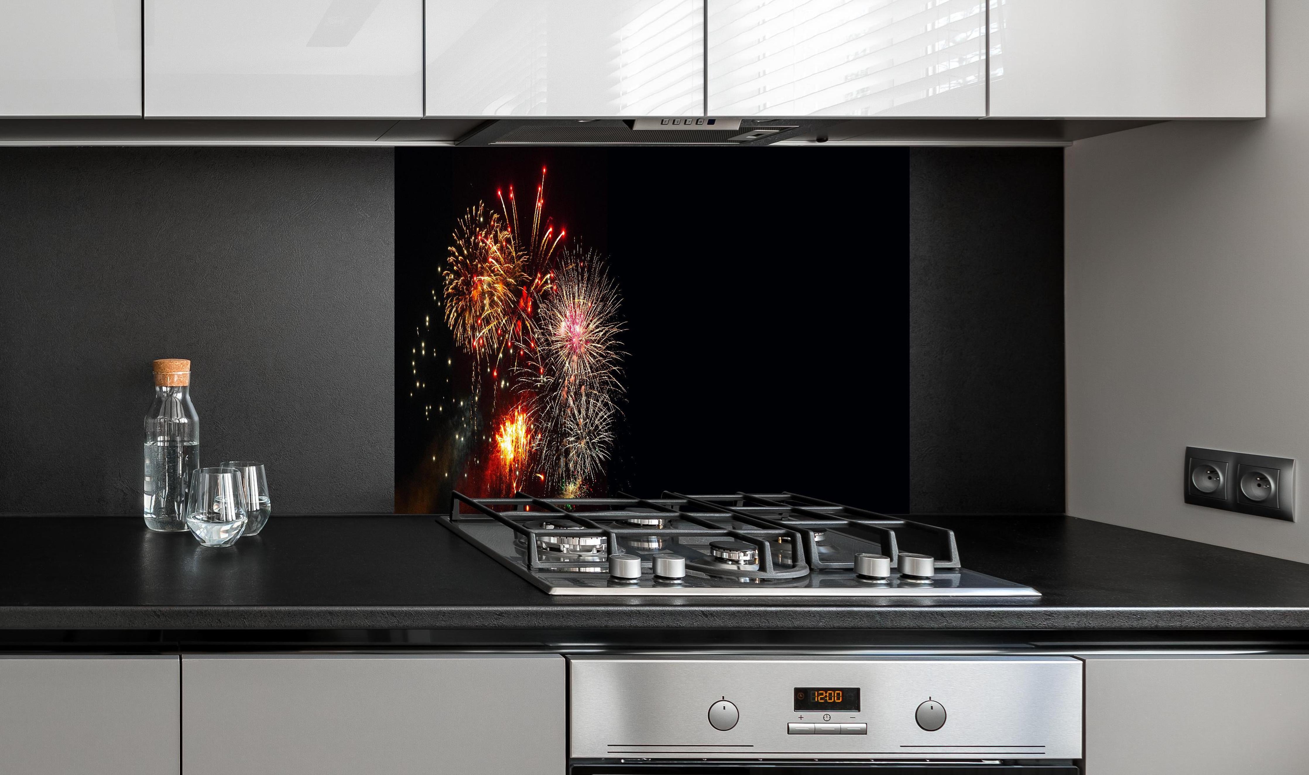 Spritzschutz - Spektakuläres Neujahrsfeuerwerk in Nacht hinter einem Cerankochfeld zwischen Holz-Kochutensilien