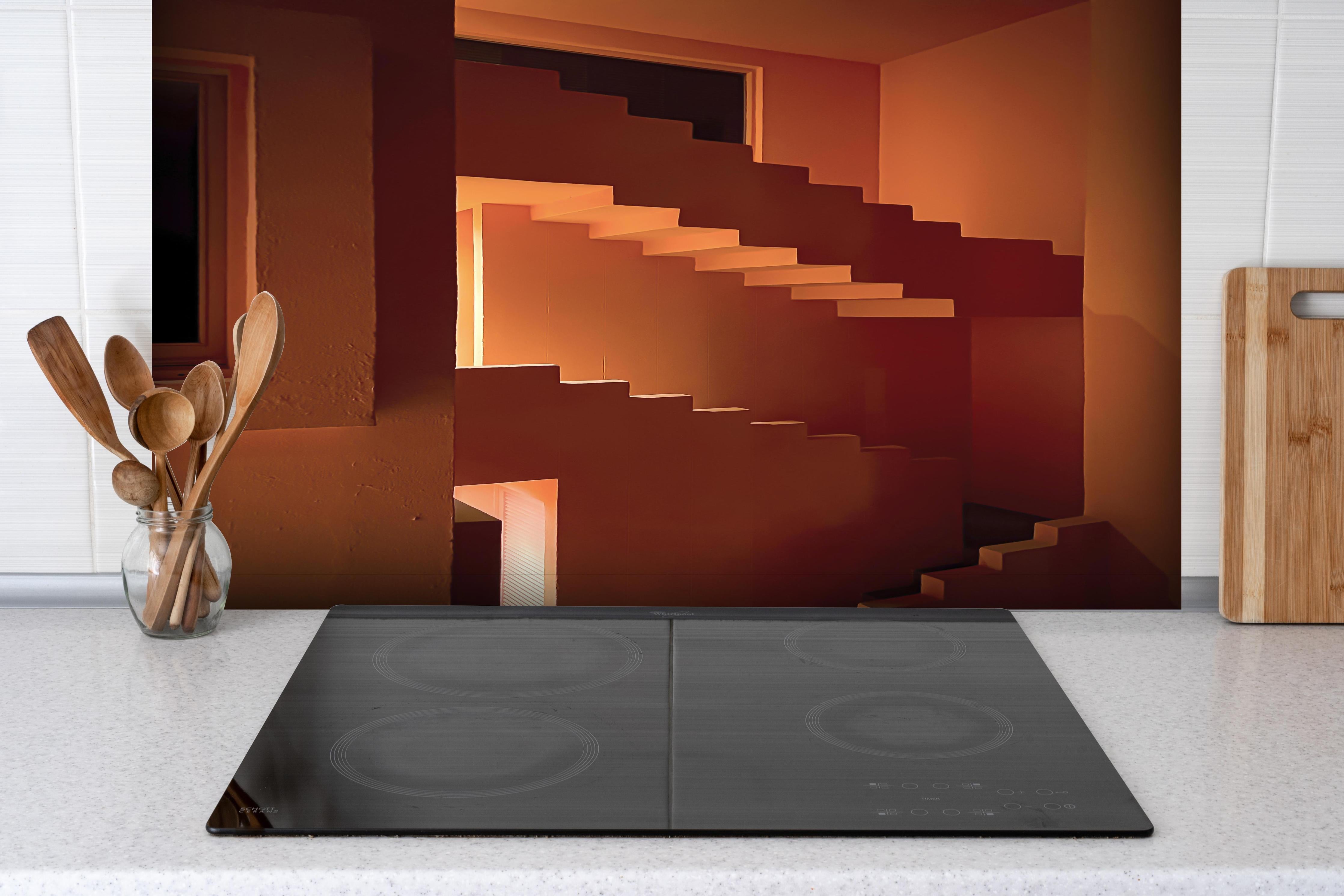 Spritzschutz - Spiralstiege in Nachtorange Architektur hinter einem Cerankochfeld zwischen Holz-Kochutensilien
