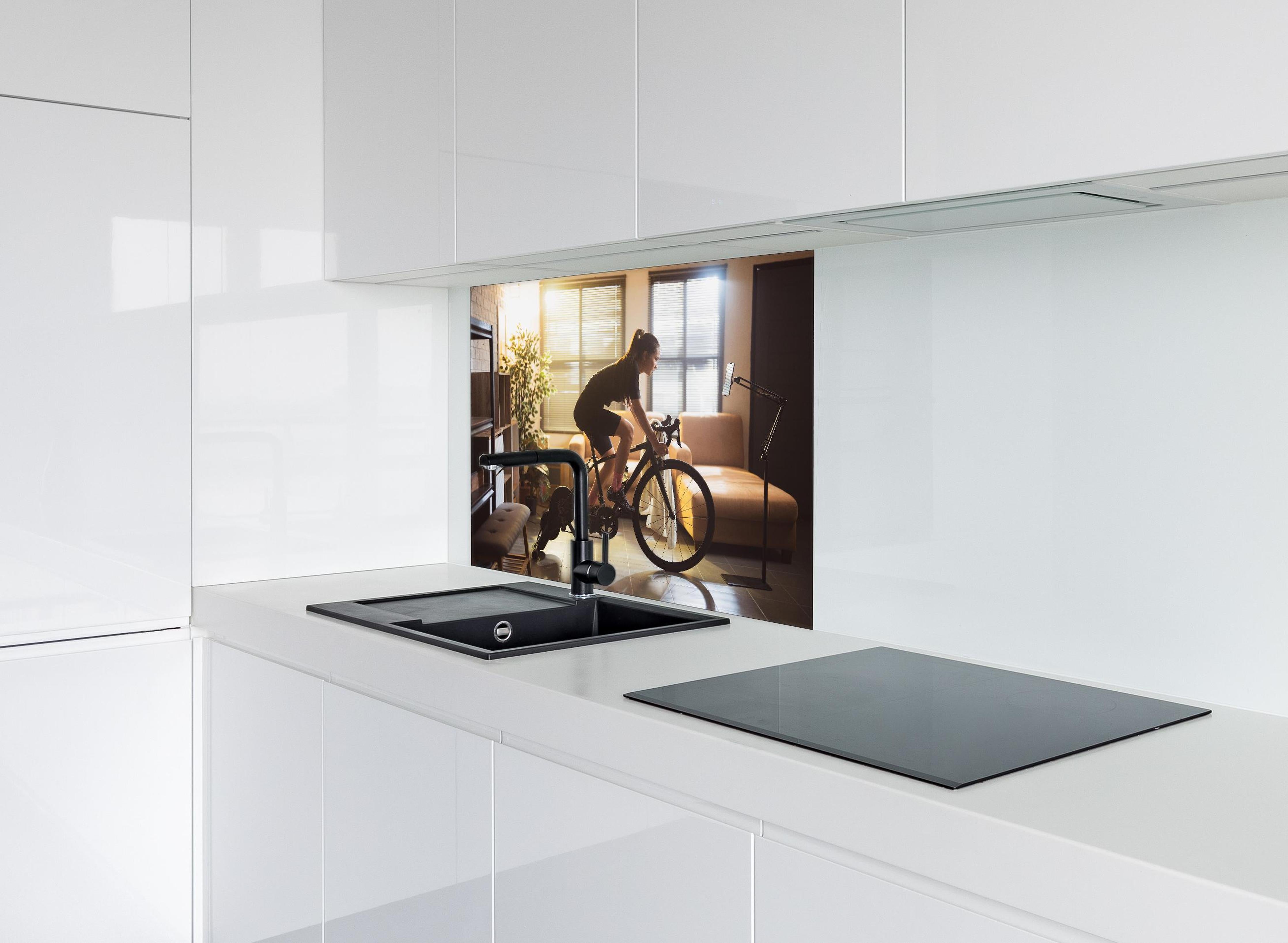 Spritzschutz - Sportliche Radfahrerin hinter einem Cerankochfeld zwischen Holz-Kochutensilien