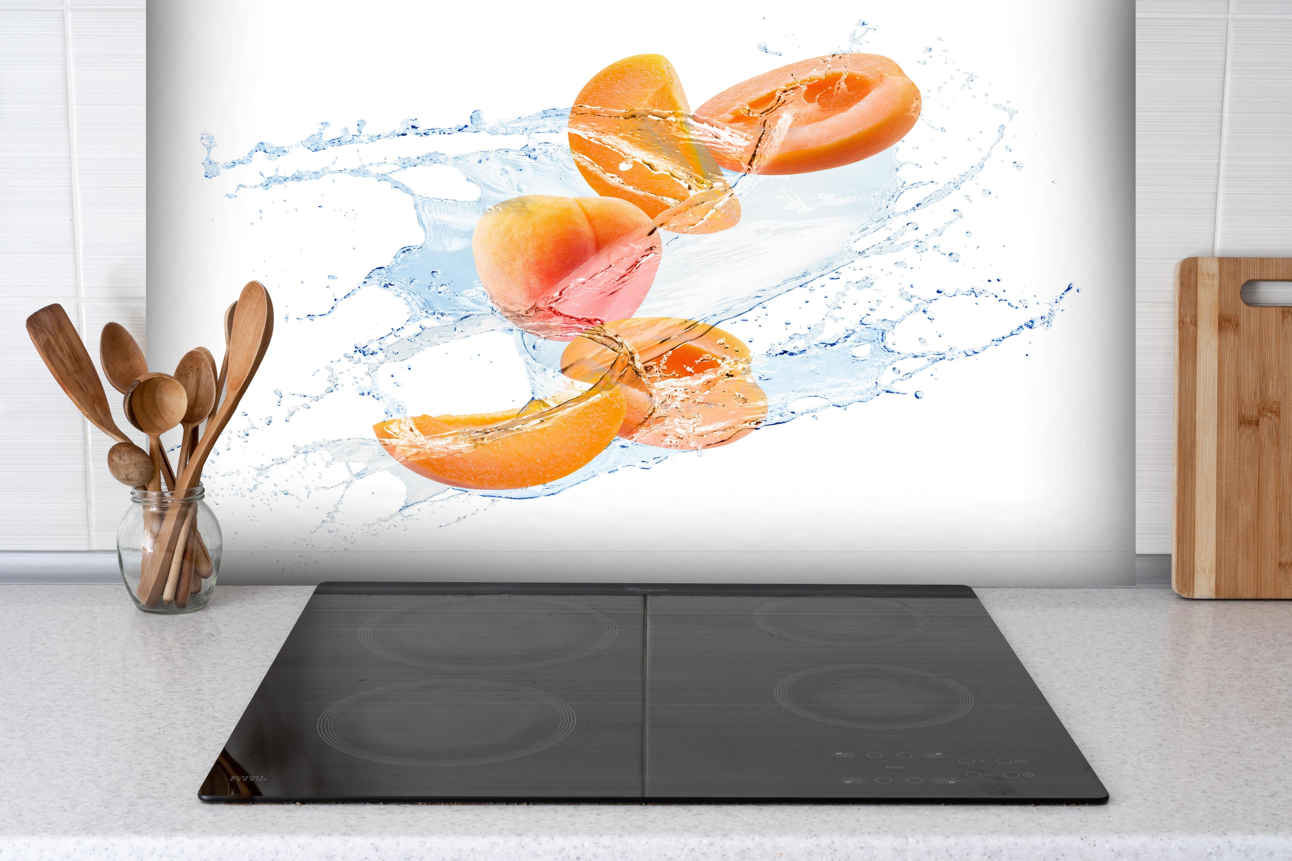 Spritzschutz - Spritzige Aprikosen hinter einem Cerankochfeld zwischen Holz-Kochutensilien