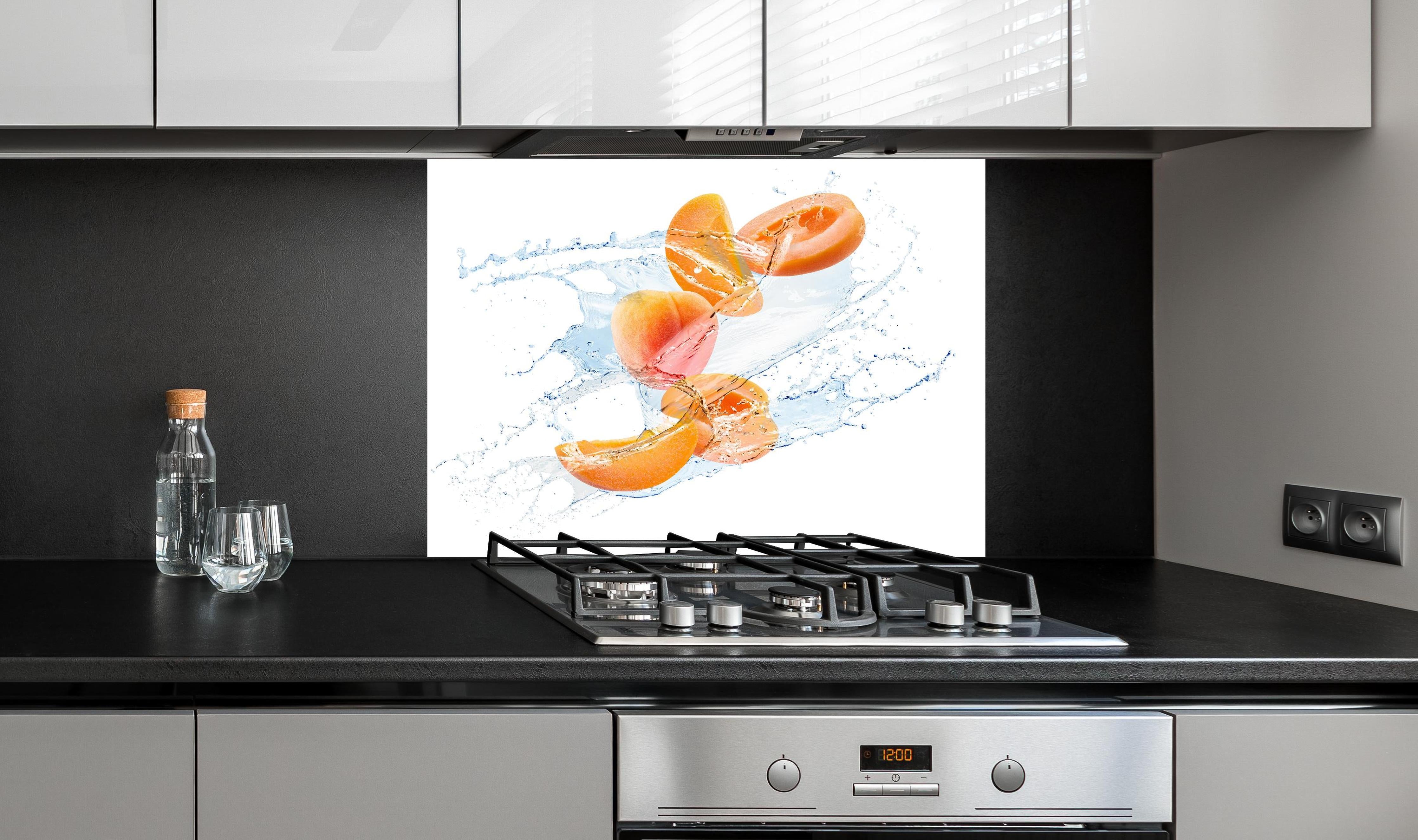 Spritzschutz - Spritzige Aprikosen hinter einem Cerankochfeld zwischen Holz-Kochutensilien