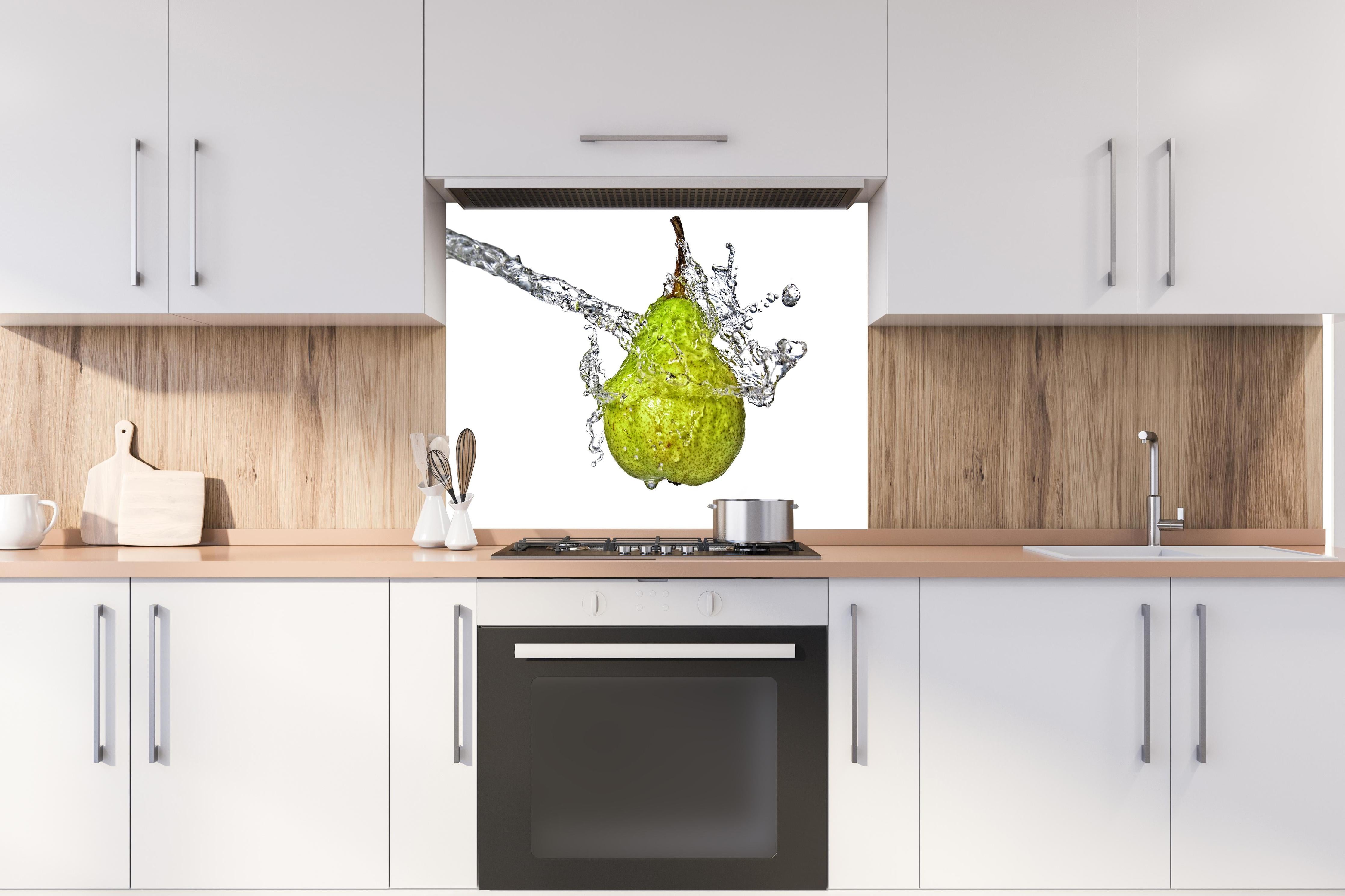 Spritzschutz - Spritzige Birne hinter einem Cerankochfeld zwischen Holz-Kochutensilien