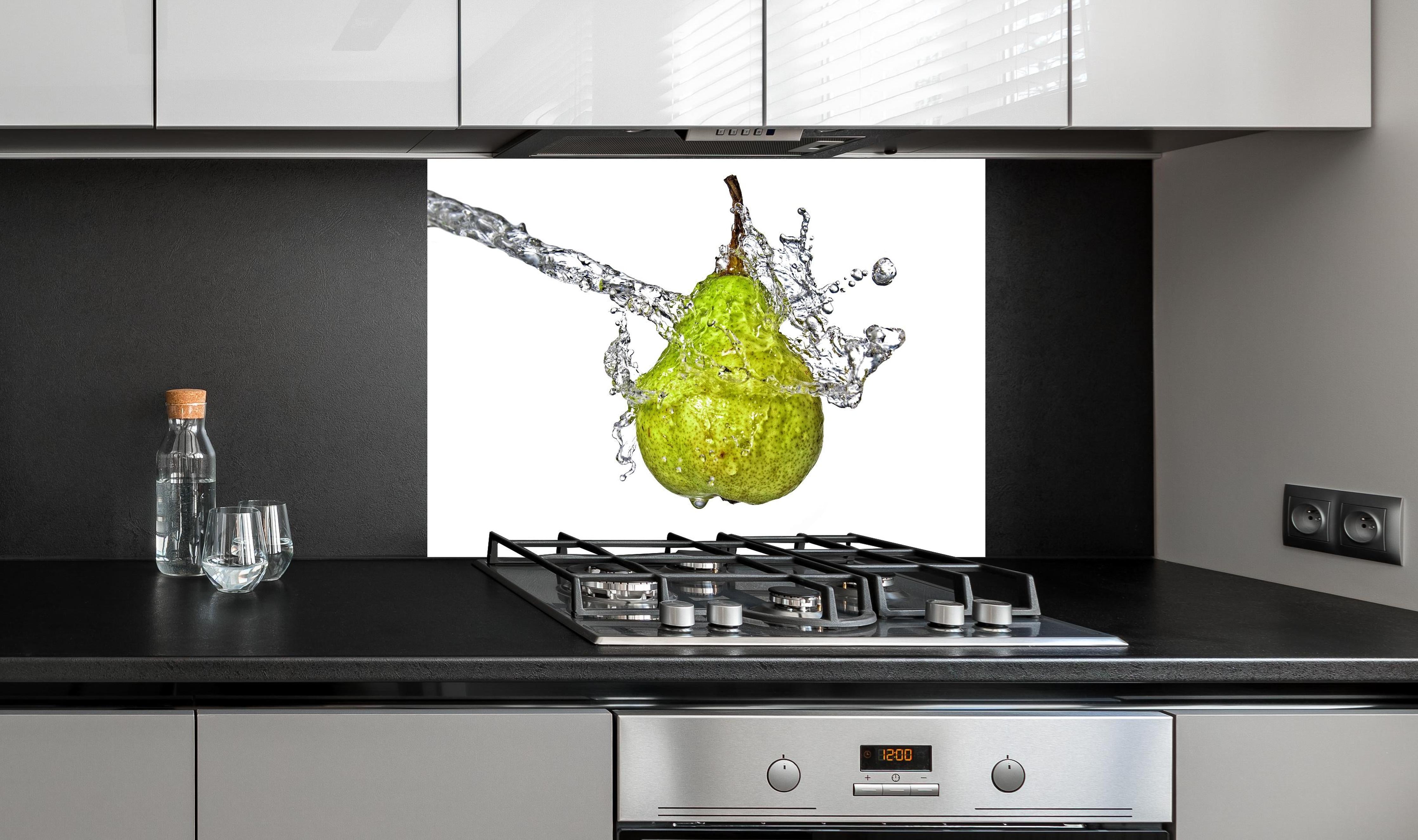 Spritzschutz - Spritzige Birne hinter einem Cerankochfeld zwischen Holz-Kochutensilien