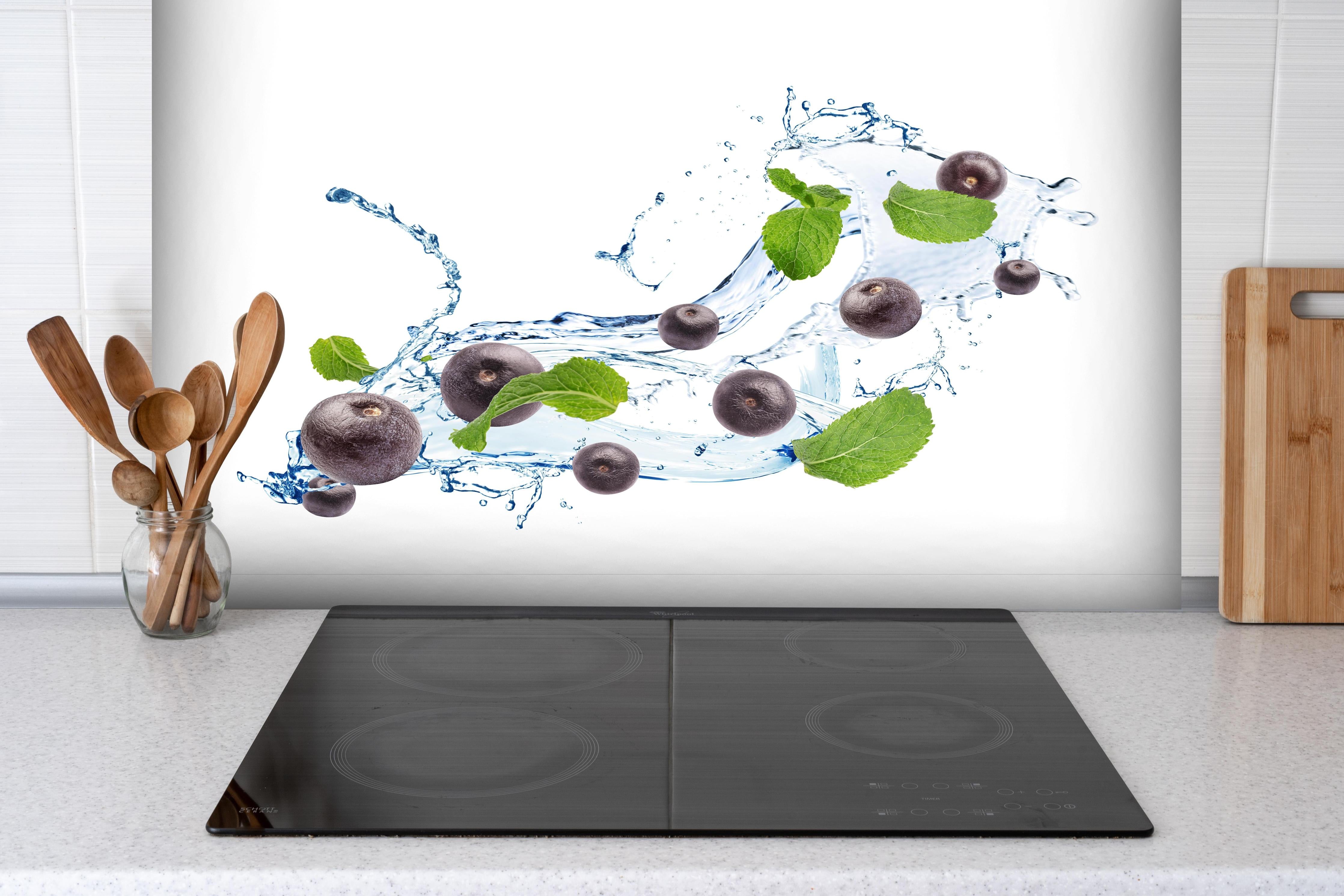 Spritzschutz - Spritzige Blaubeeren hinter einem Cerankochfeld zwischen Holz-Kochutensilien