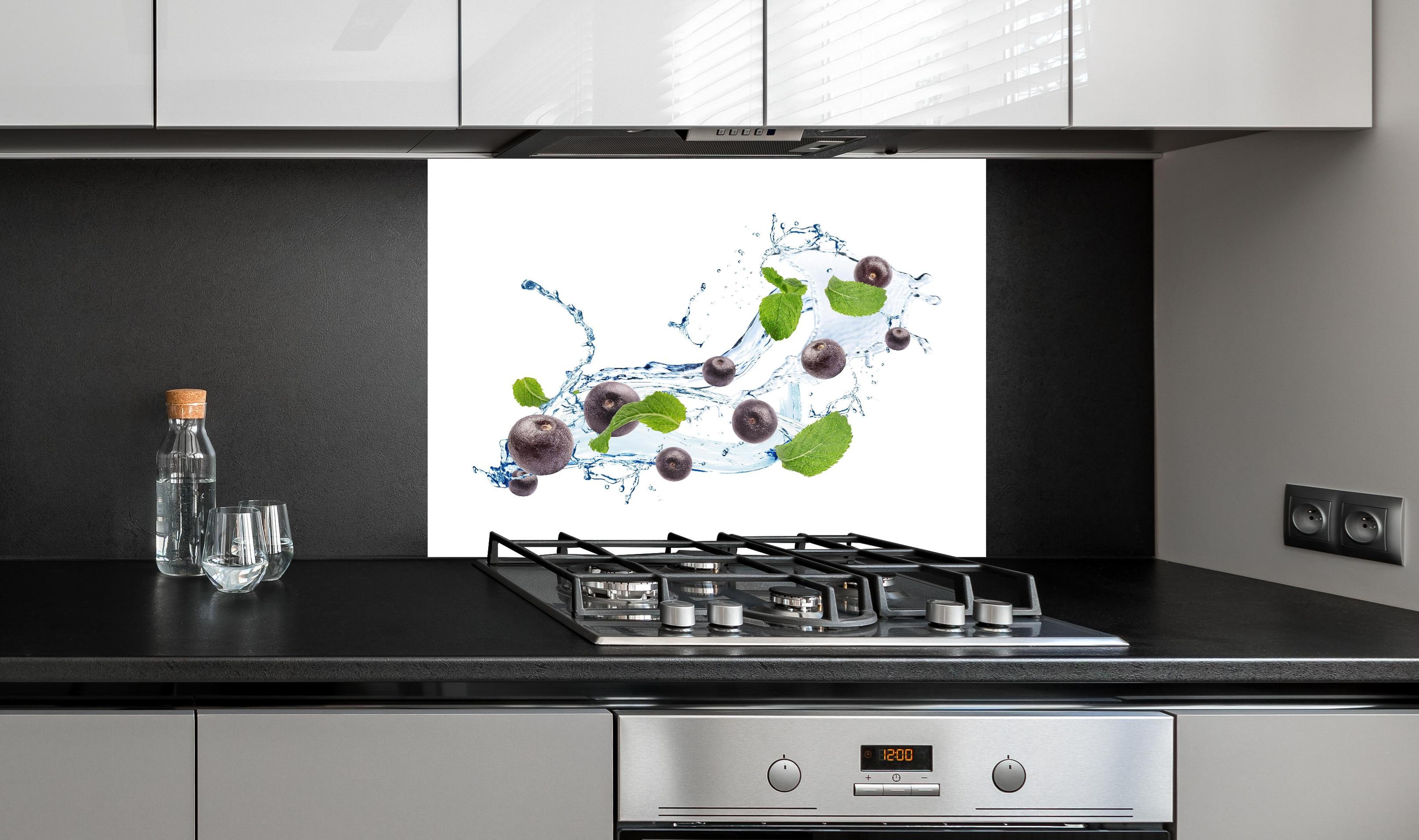 Spritzschutz - Spritzige Blaubeeren hinter einem Cerankochfeld zwischen Holz-Kochutensilien
