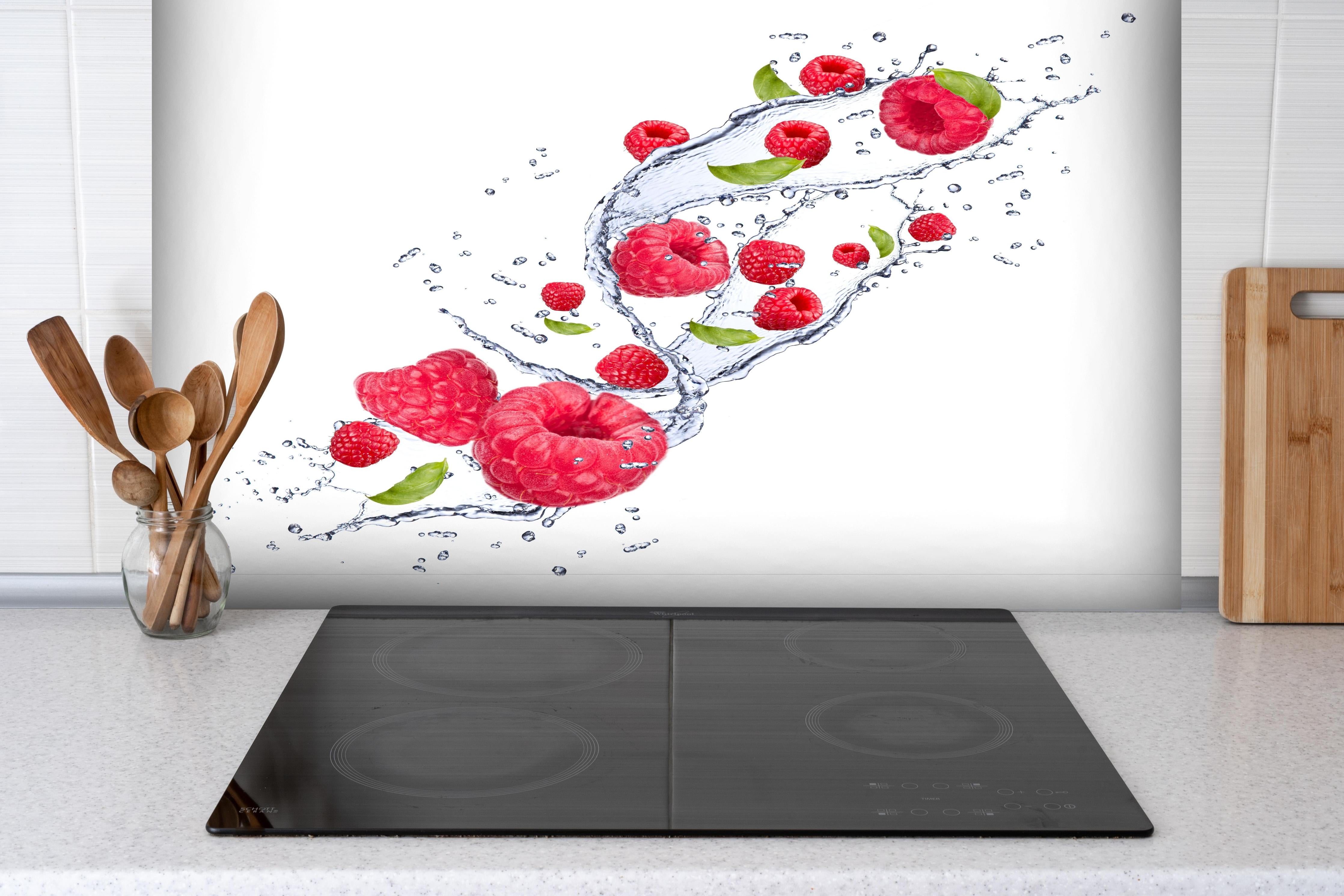 Spritzschutz - Spritzige Erdbeeren hinter einem Cerankochfeld zwischen Holz-Kochutensilien