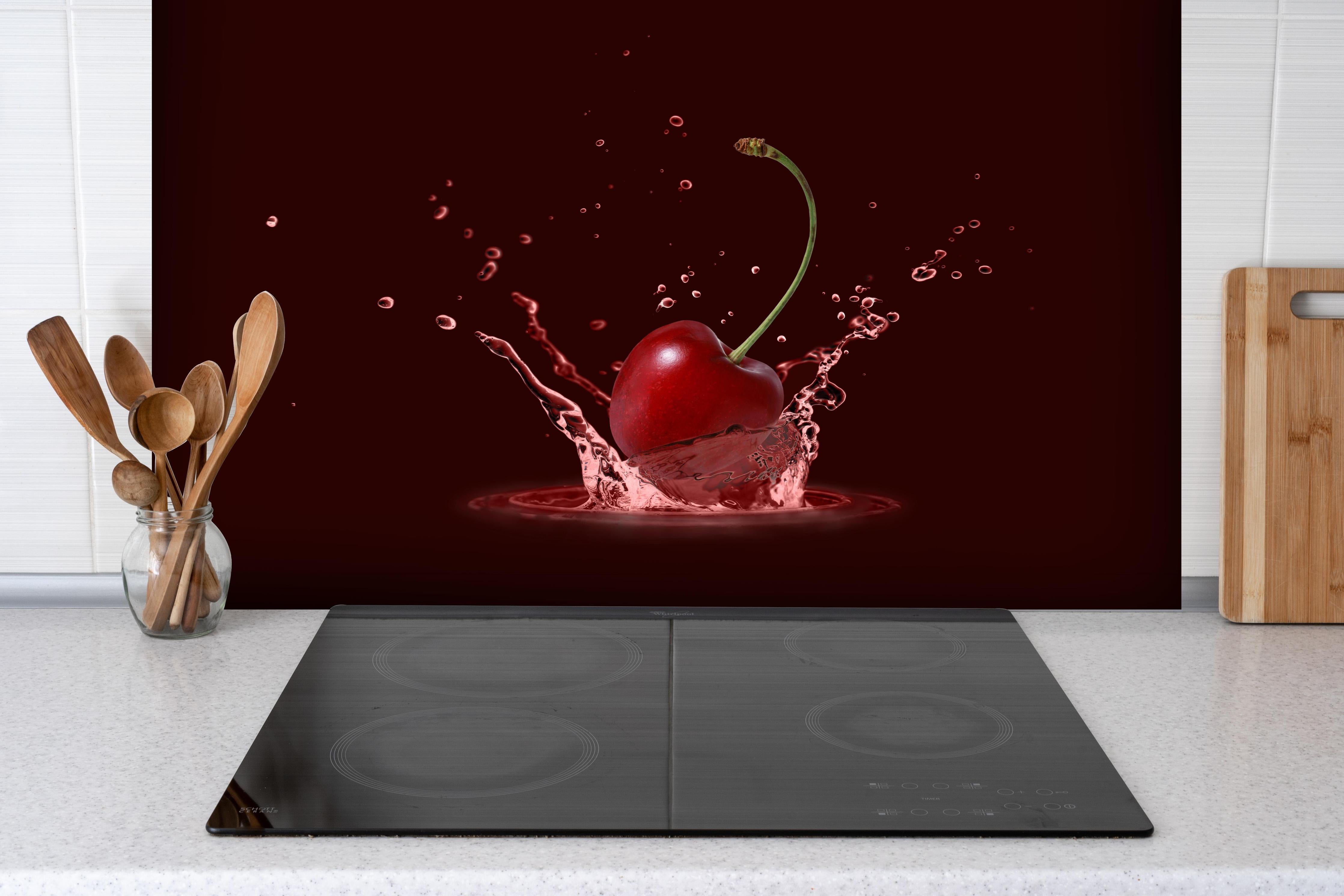 Spritzschutz - Spritzige Kirsche hinter einem Cerankochfeld zwischen Holz-Kochutensilien
