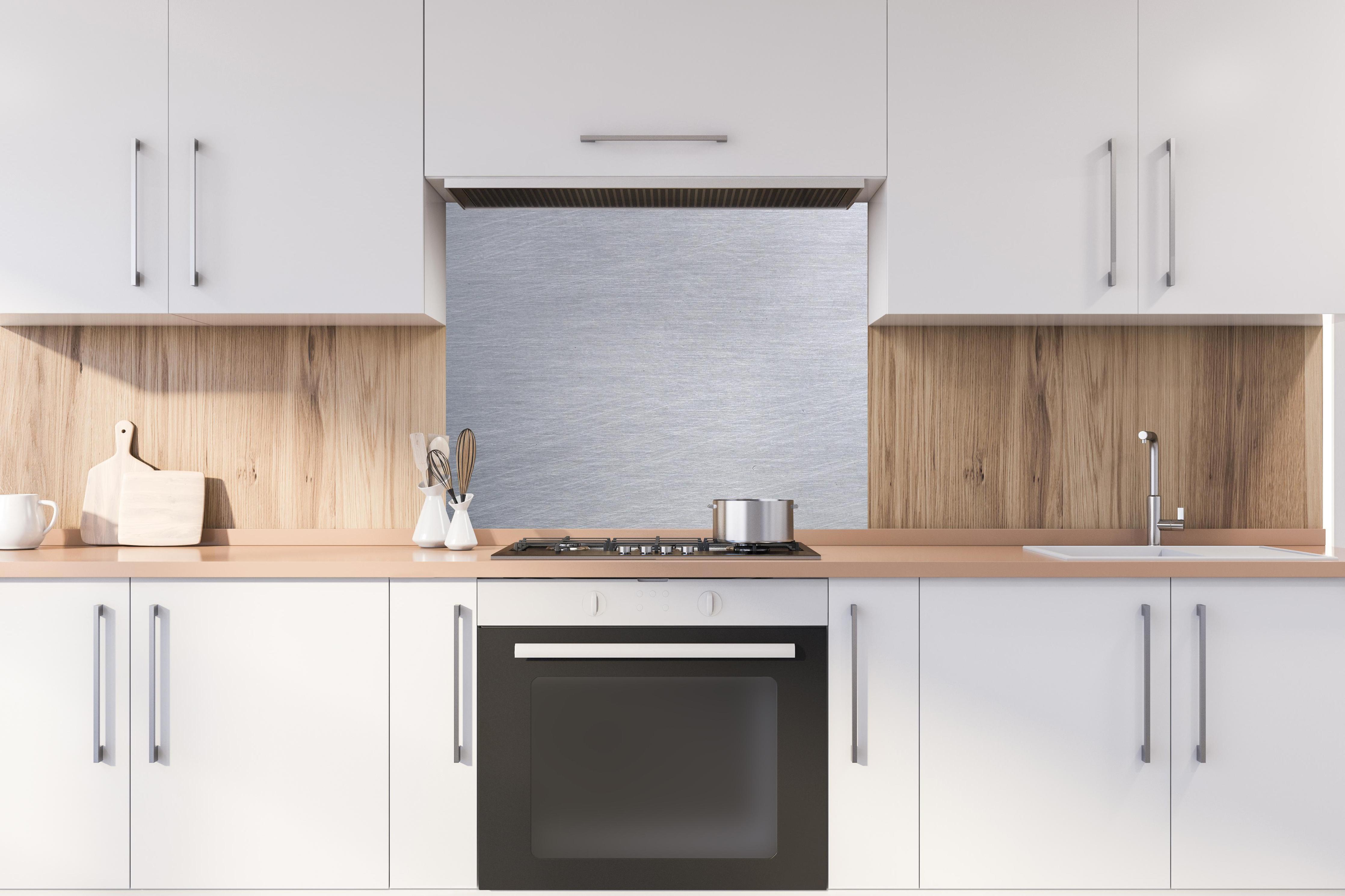 Spritzschutz - Gebürsteter Stahl hinter stilvollem Gasherd unter Dunstabzugshaube