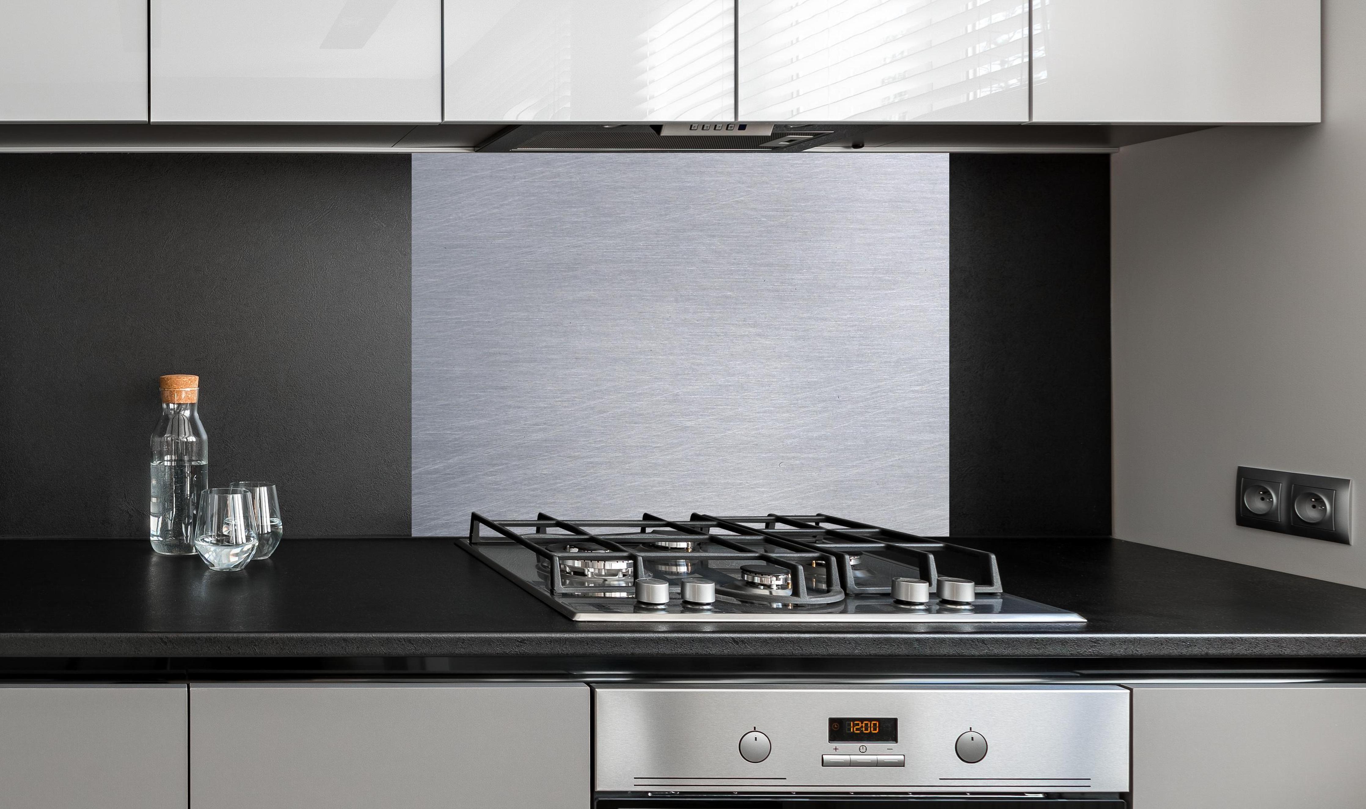 Spritzschutz - Gebürsteter Stahl an edler Anthrazit-Wand hinter silbernem Gasherd