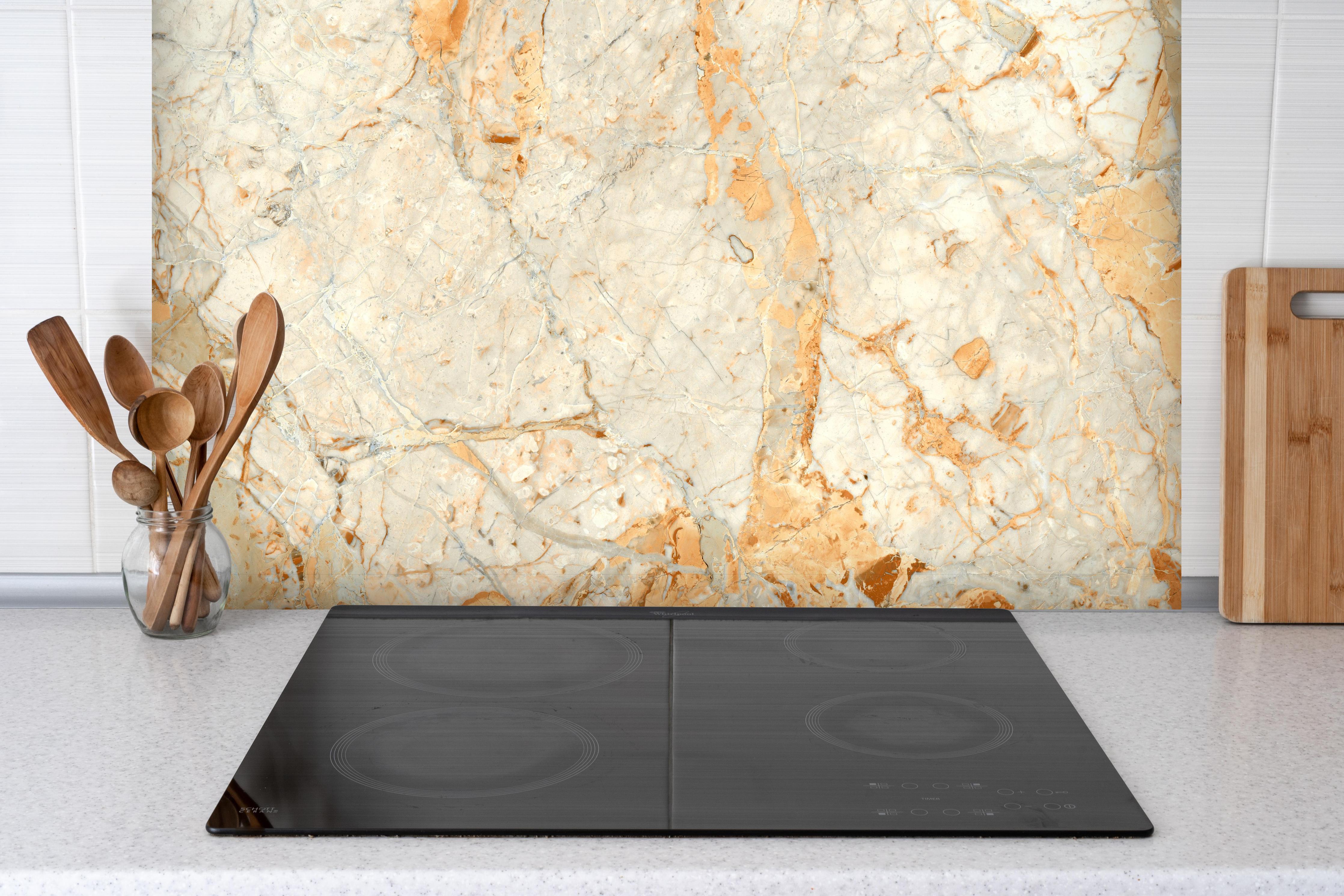 Spritzschutz - Rötlich-beiger Marmor hinter einem Cerankochfeld zwischen Holz-Kochutensilien